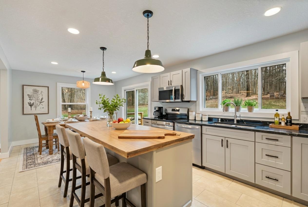 Image 1: Kitchen with stainless steel appliances, wooden counters, decorative light fixtures, a kitchen bar, and gray cabinetry, Kitchen Image 1: Kitchen with stainless steel appliances, wooden counters, decorative light fixtures, a kitchen bar, and gray cabinetry, Kitchen