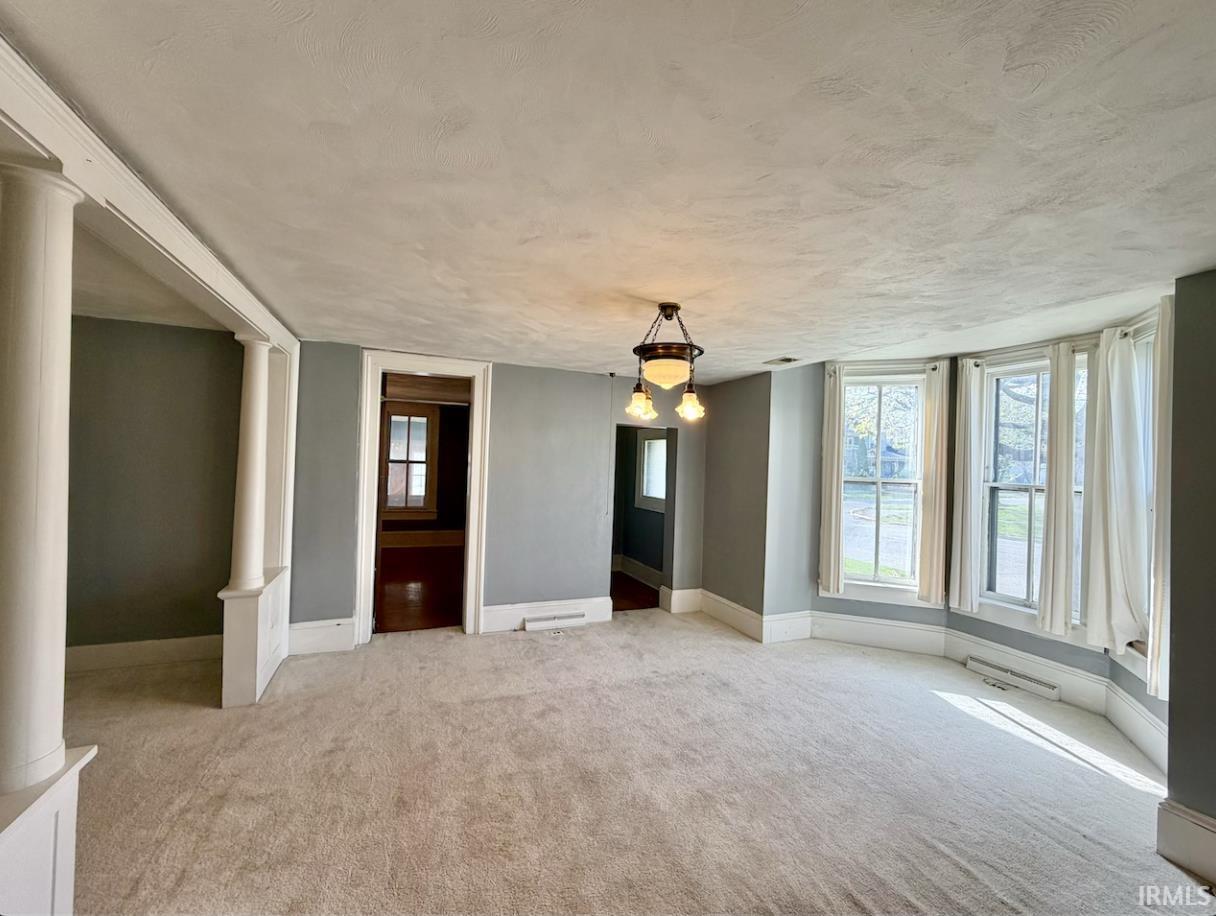Image 2: Spare room featuring decorative columns, light carpet, and a textured ceiling, Other