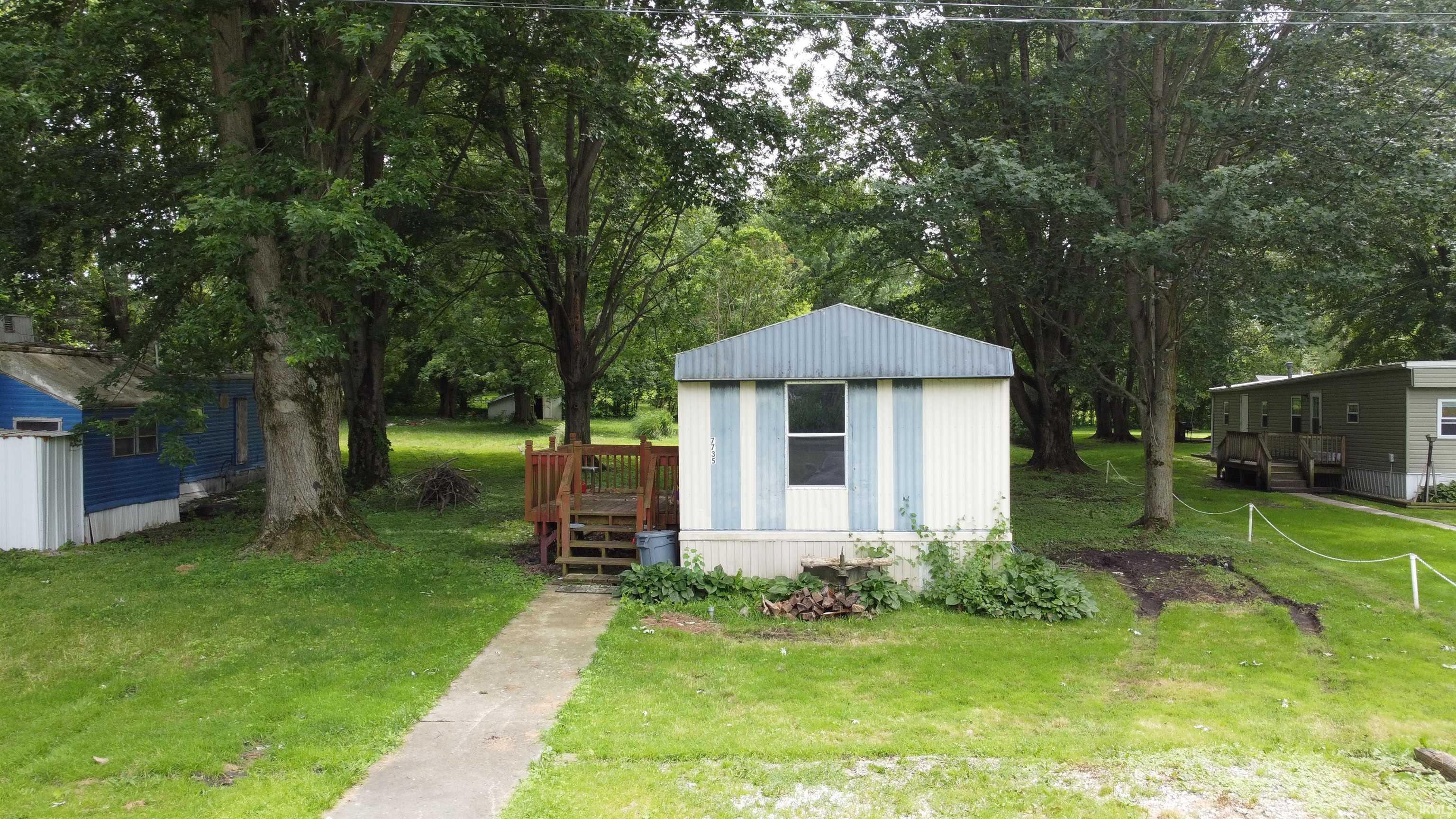Image 0: Manufactured home with vertical light blue and white siding, featuring a wood deck entry with stairs, Out Buildings Image 0: Manufactured home with vertical light blue and white siding, featuring a wood deck entry with stairs, Out Buildings
