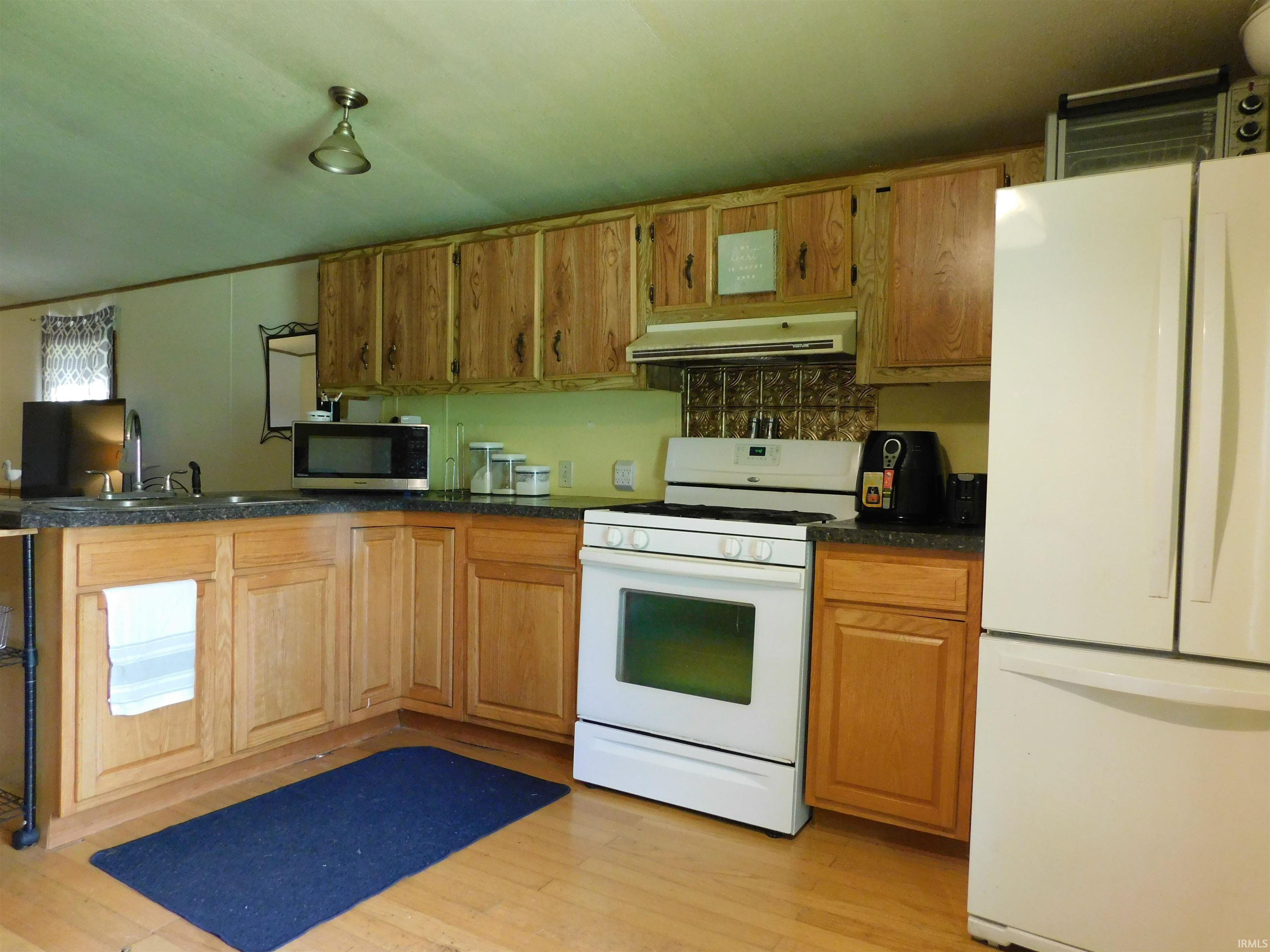 Image 2: Kitchen featuring light wood cabinetry, dark speckled countertops, and wood-finish flooring, Kitchen Image 2: Kitchen featuring light wood cabinetry, dark speckled countertops, and wood-finish flooring, Kitchen