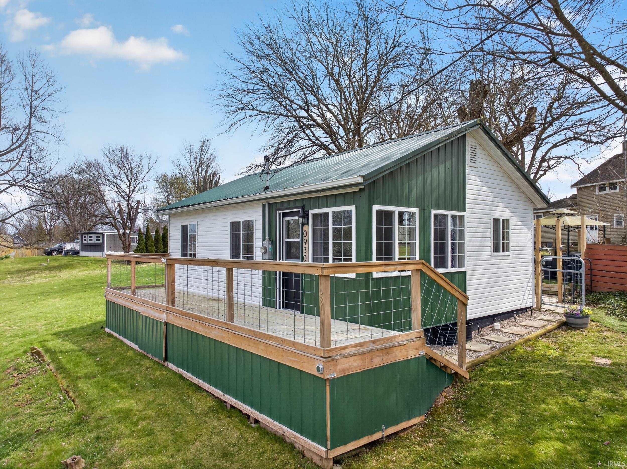 Image 1: Rear view of property with a wooden deck, a lawn, and a metal roof, Back Of Structure Image 1: Rear view of property with a wooden deck, a lawn, and a metal roof, Back Of Structure