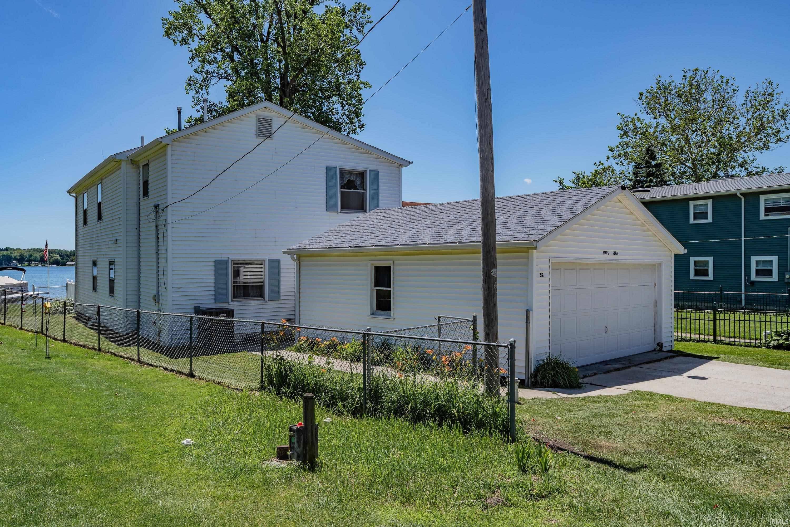 Image 2: Two-story residence with white siding, an attached garage, and a chain-link fence enclosing the rear yard, Side Of Structure Image 2: Two-story residence with white siding, an attached garage, and a chain-link fence enclosing the rear yard, Side Of Structure