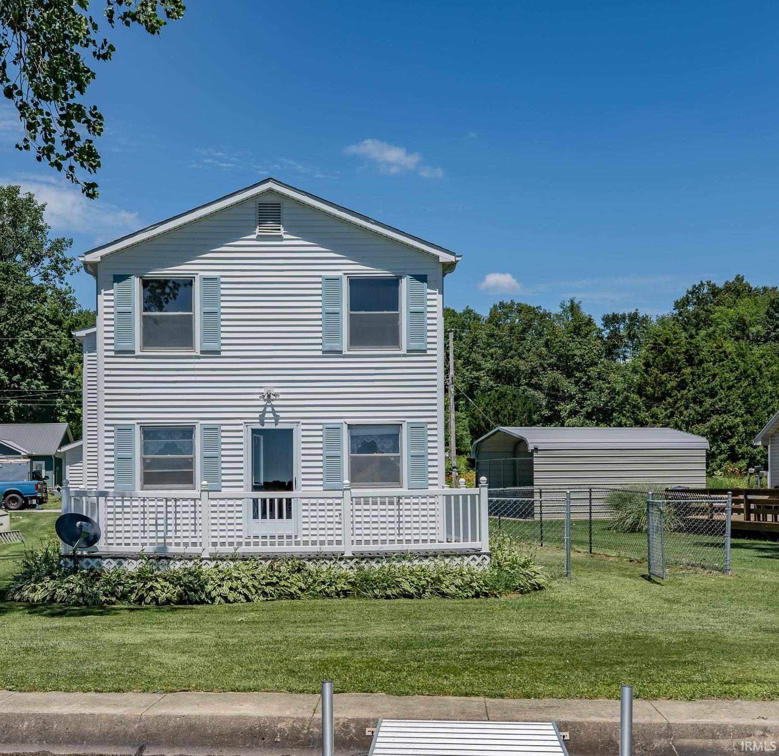 Image 3: Two-story residence featuring light-colored siding, contrasting blue shutters, and a front porch with white railings, Front of the Structure Image 3: Two-story residence featuring light-colored siding, contrasting blue shutters, and a front porch with white railings, Front of the Structure