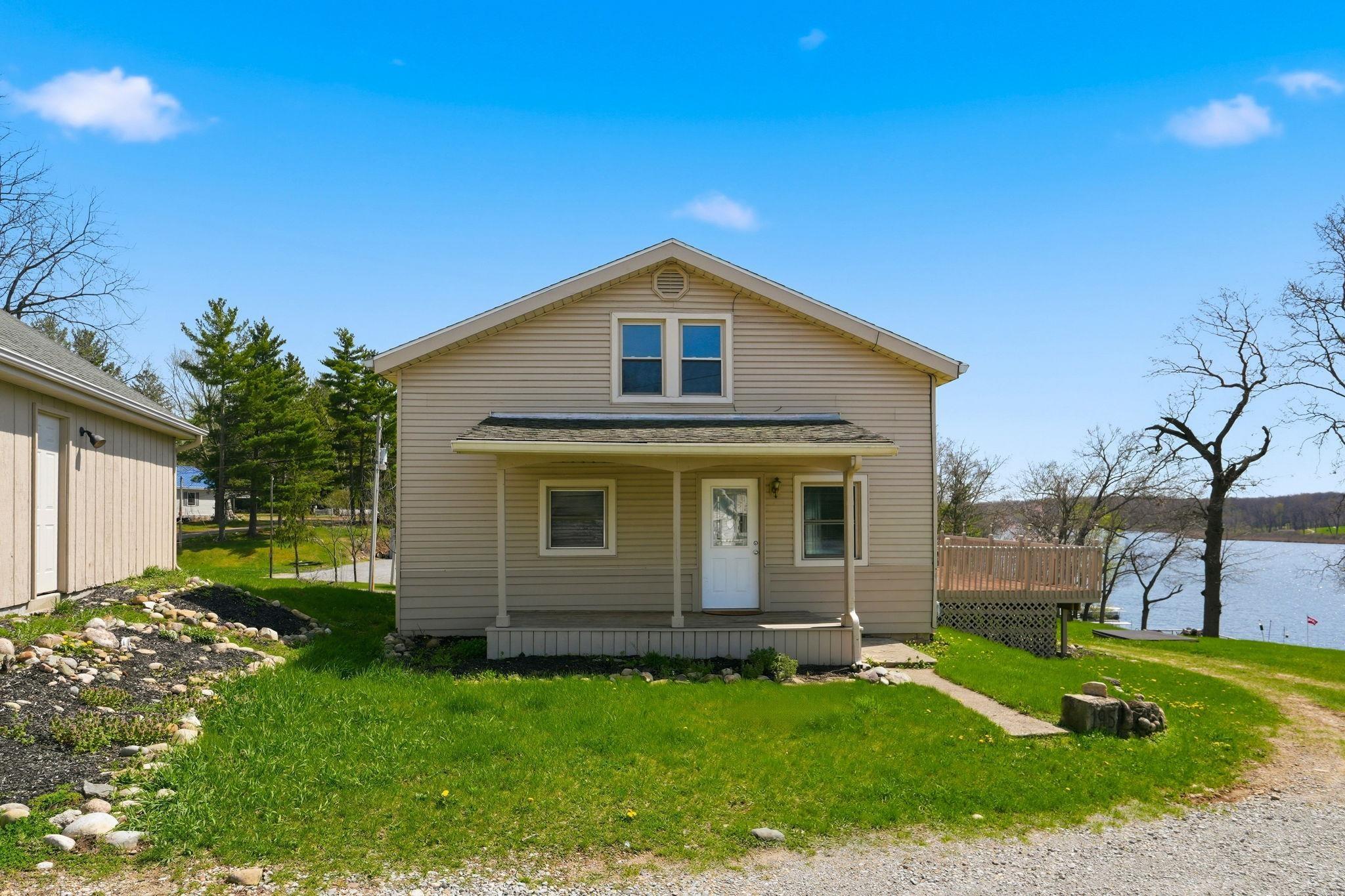 Image 1: View of front facade with a front yard, a water view, and covered porch, Front Of Structure