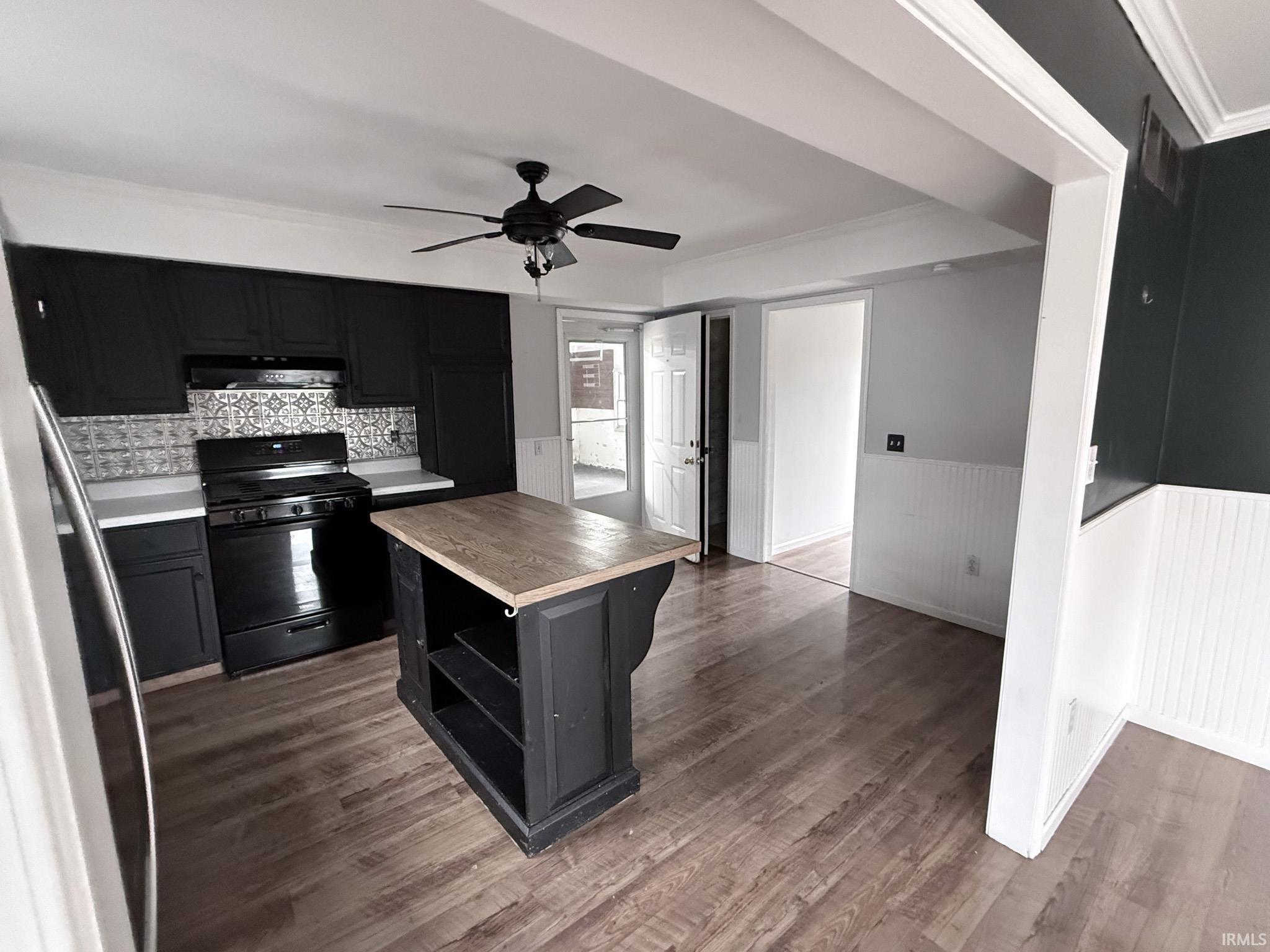 Image 2: Kitchen with dark cabinets, wainscoting, ornamental molding, black gas range, and wooden counters, Kitchen Image 2: Kitchen with dark cabinets, wainscoting, ornamental molding, black gas range, and wooden counters, Kitchen