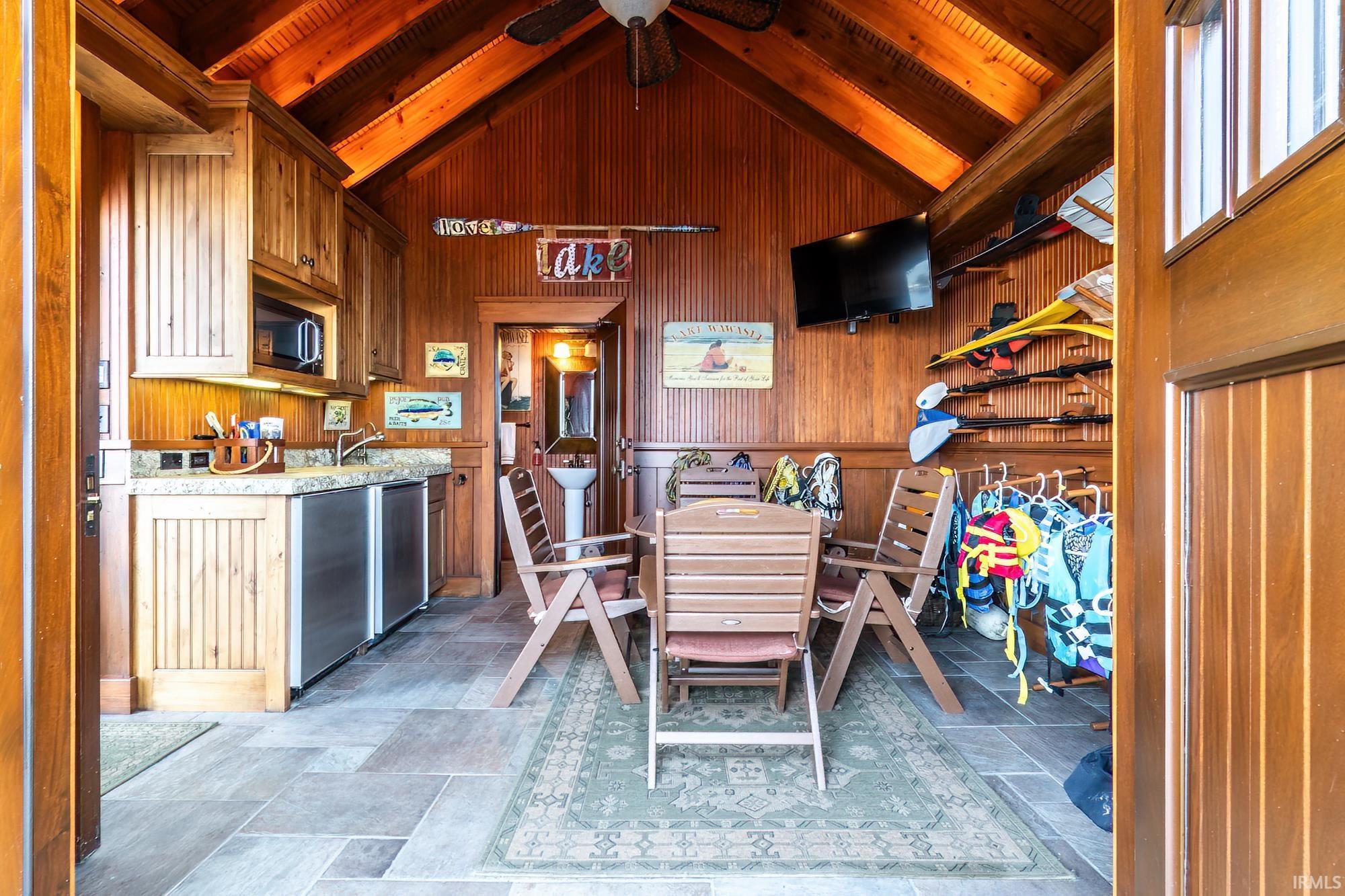 Image 3: Dining room featuring wood walls, light stone finish flooring, a ceiling fan, and a wood ceiling with exposed beams, Dining Area