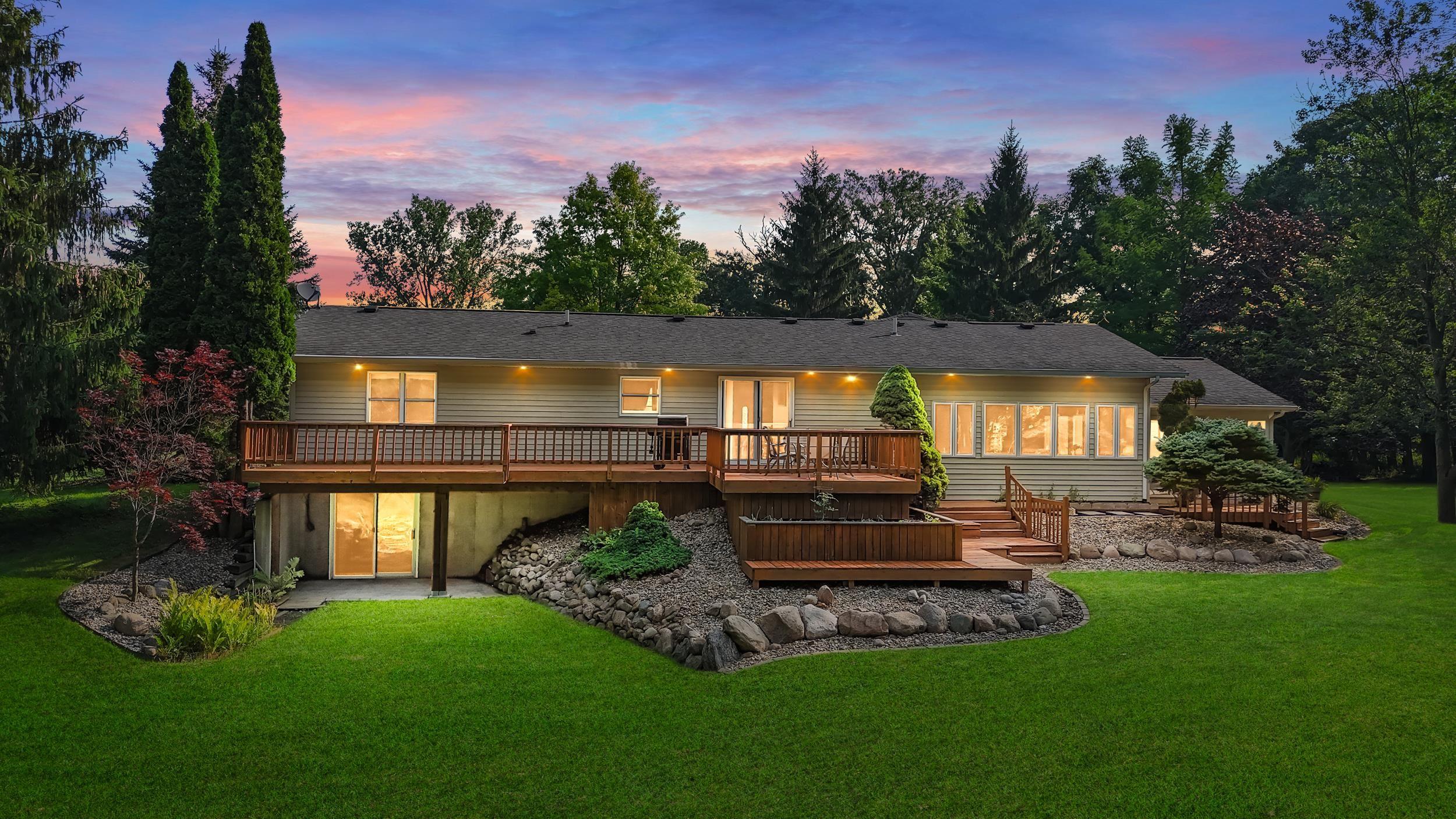Image 0: Rear exterior featuring a multi-level wood deck, expansive green lawn, and mature trees, Back Of Structure