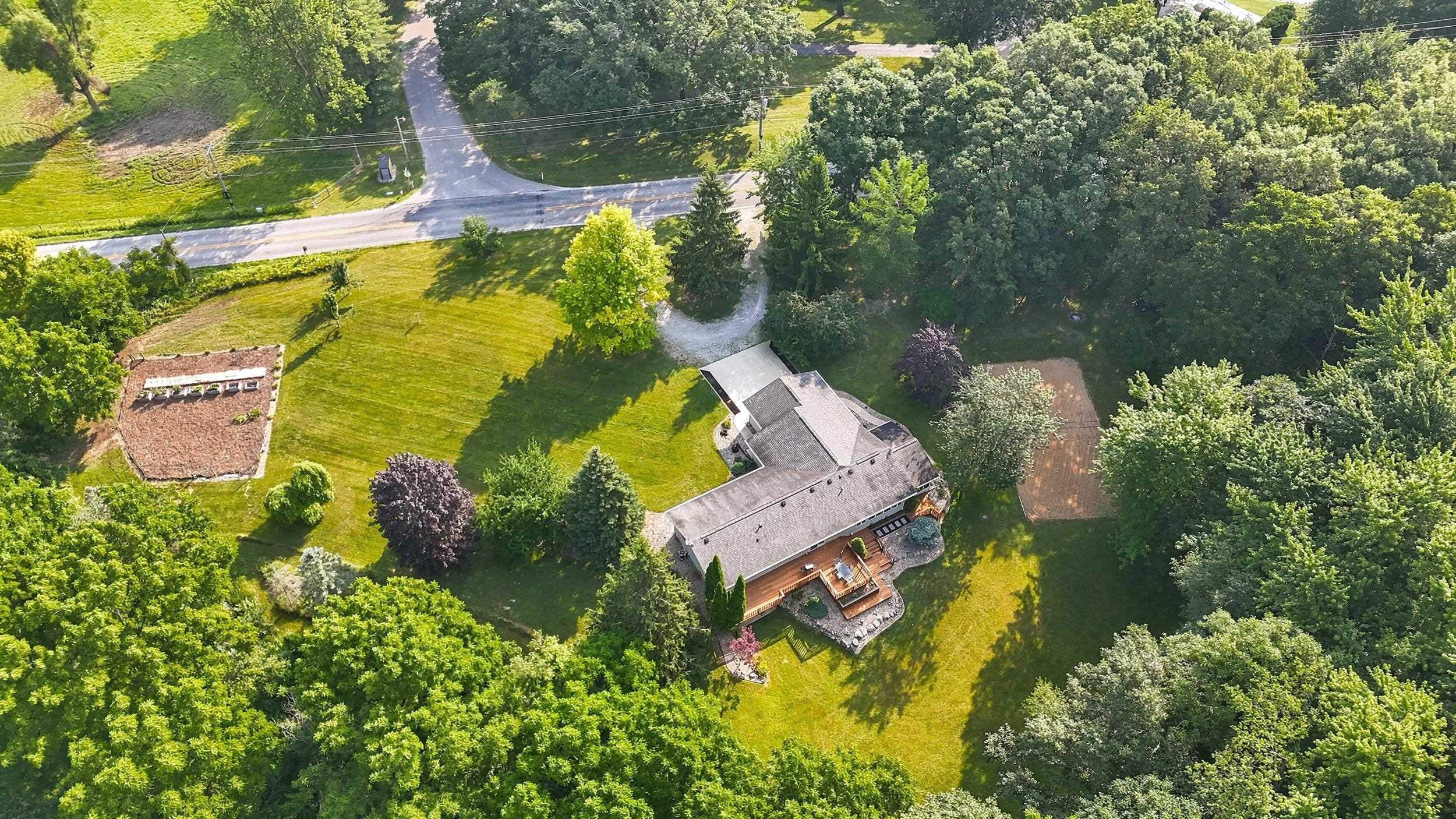 Image 1: Expansive property featuring a multi-level structure, a large wooden deck, and extensive tree coverage, Aerial View