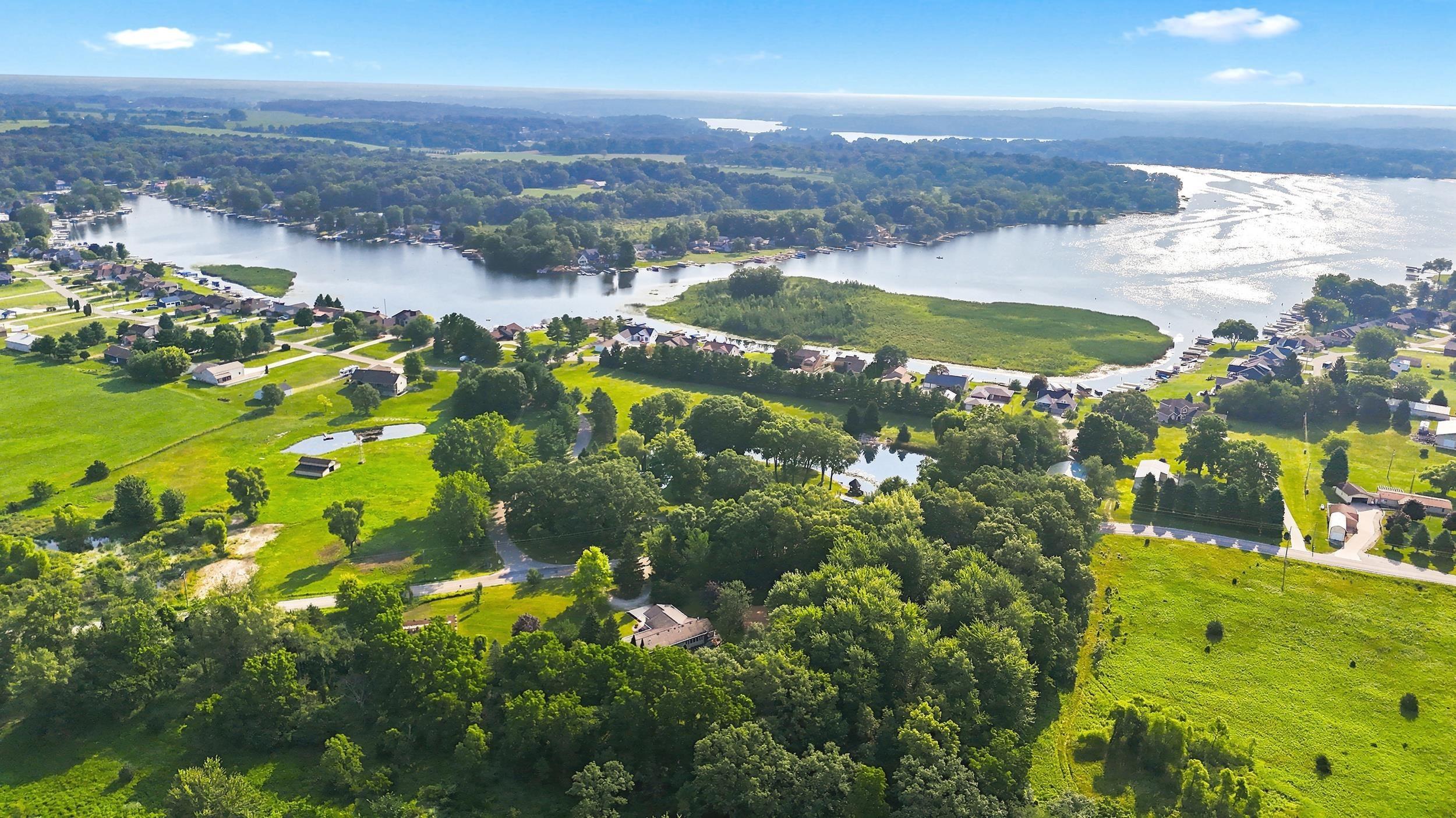 Image 3: Expansive property featuring a tranquil pond surrounded by mature trees, large green spaces, and a winding road, Aerial View