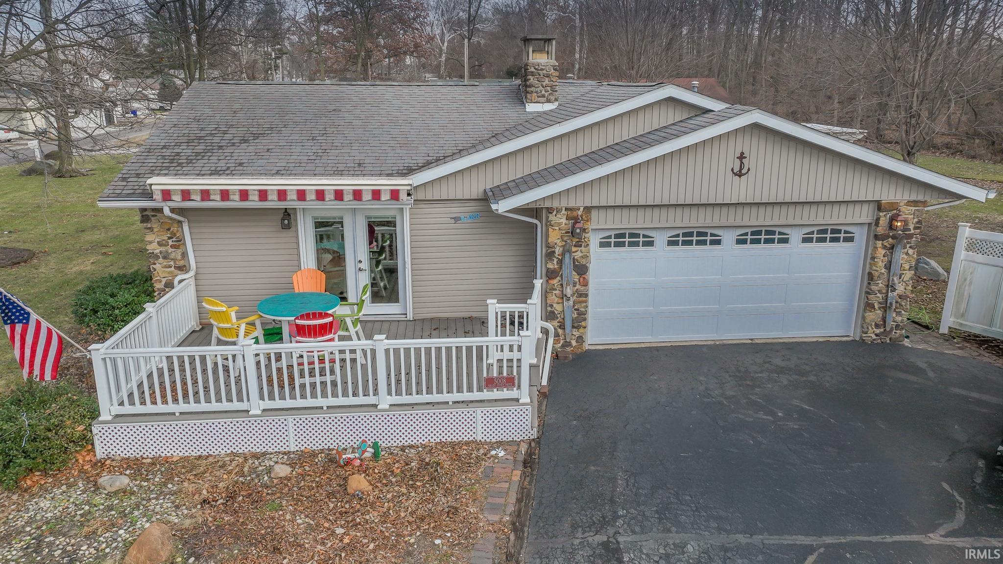 Image 2: View of front of property with a wooden deck, asphalt driveway, roof with shingles, an attached garage, and a chimney, Front Of Structure