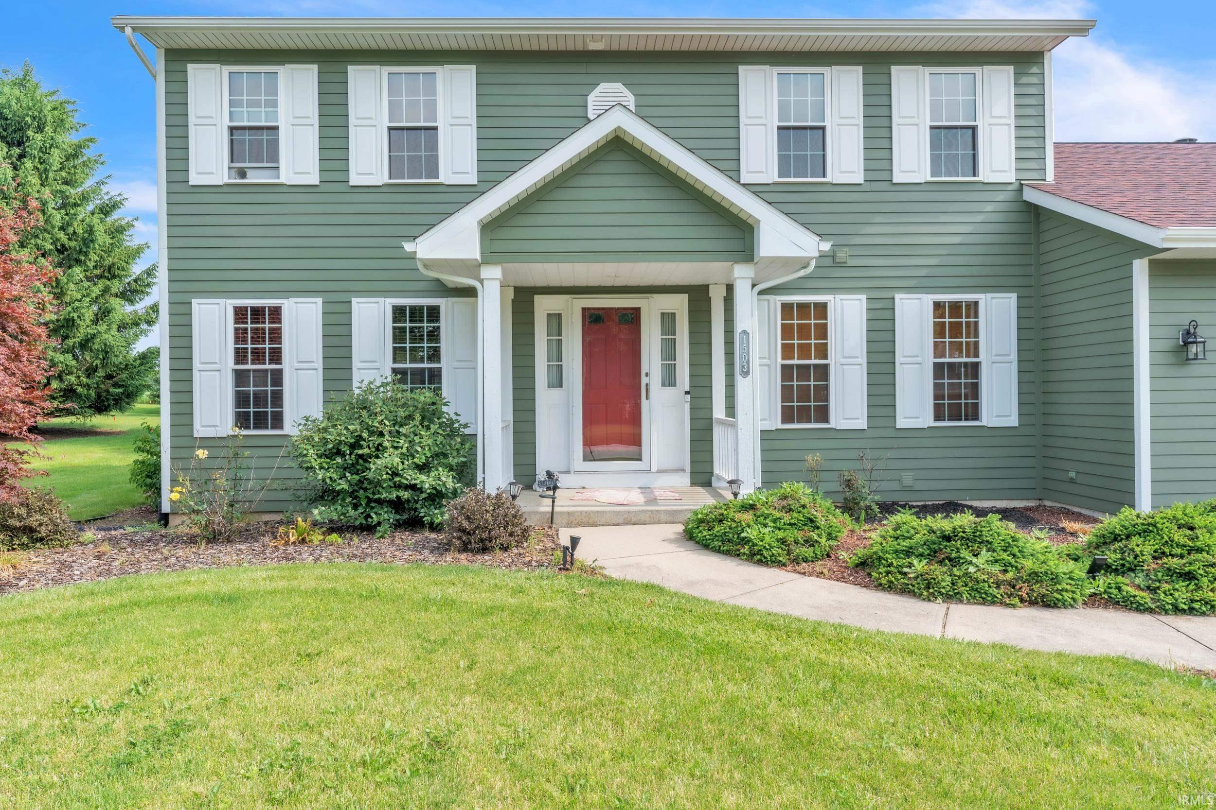 Image 1: Two-story residence featuring green siding and white window shutters, Front Of Structure