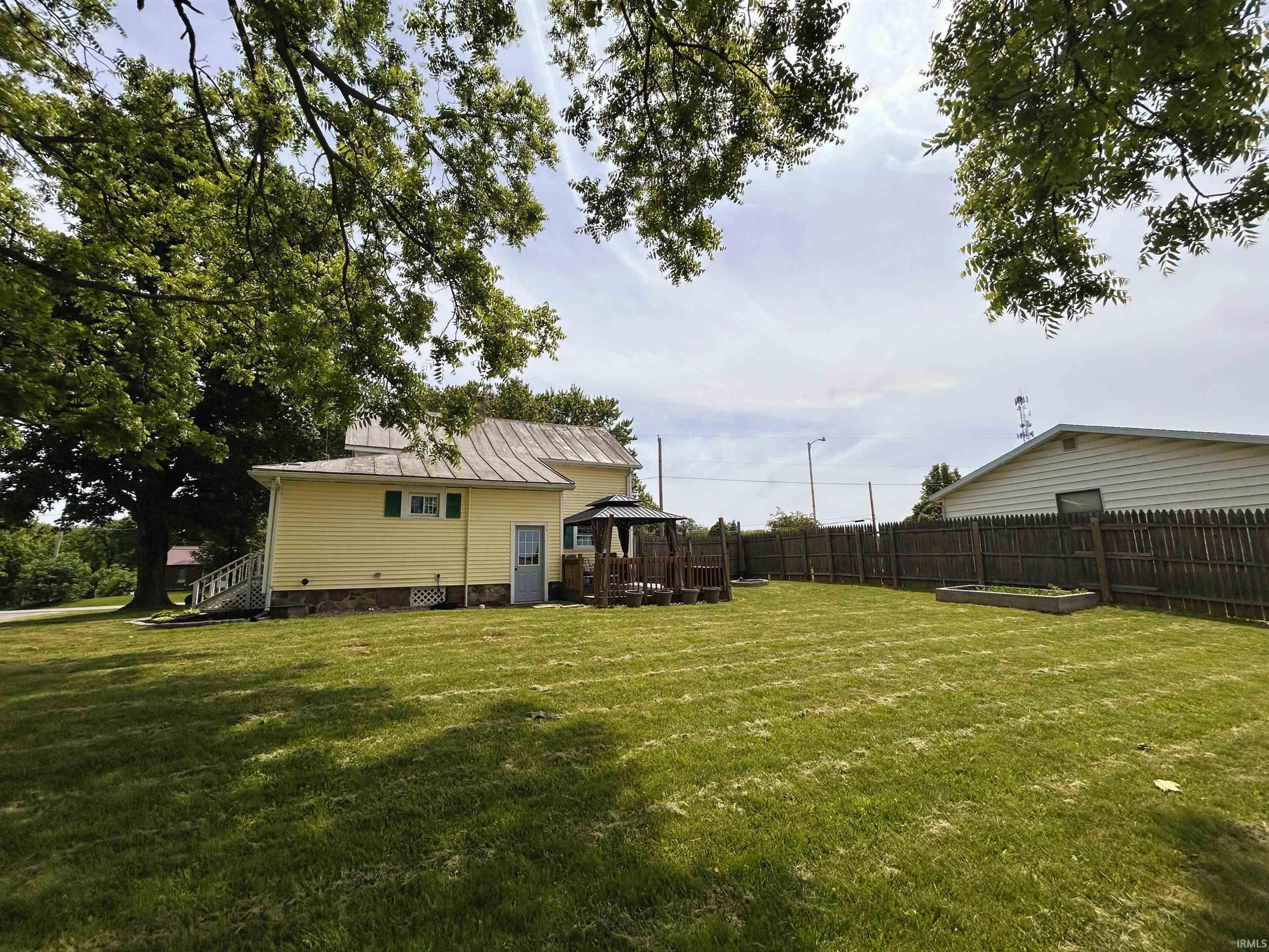 Image 3: Expansive rear yard featuring a wooden privacy fence, a built-in wooden planter box, and mature trees providing natural shade, Back Of Structure Image 3: Expansive rear yard featuring a wooden privacy fence, a built-in wooden planter box, and mature trees providing natural shade, Back Of Structure