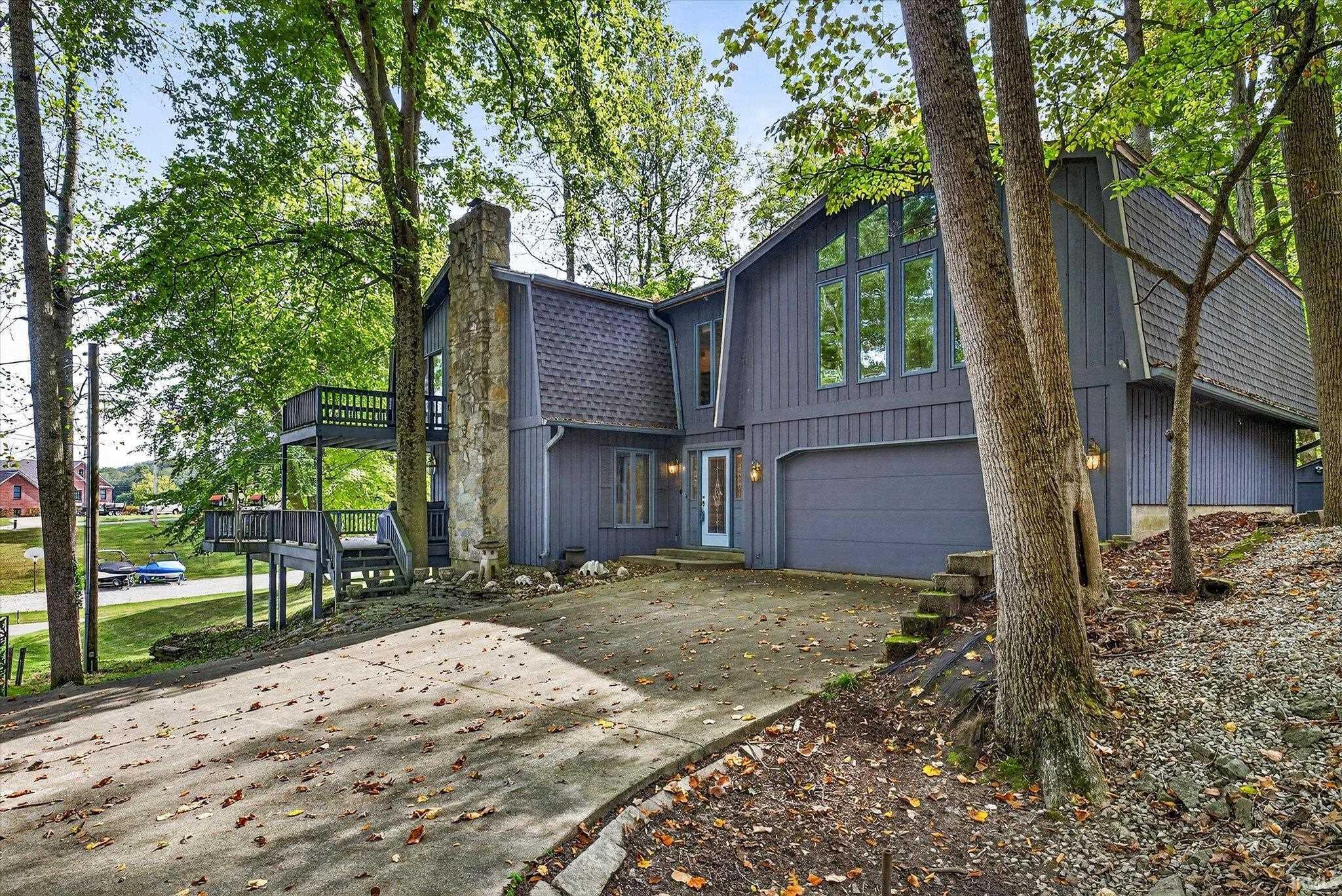 Image 2: View of front of home with an attached garage, a chimney, driveway, and a deck, Front Of Structure Image 2: View of front of home with an attached garage, a chimney, driveway, and a deck, Front Of Structure