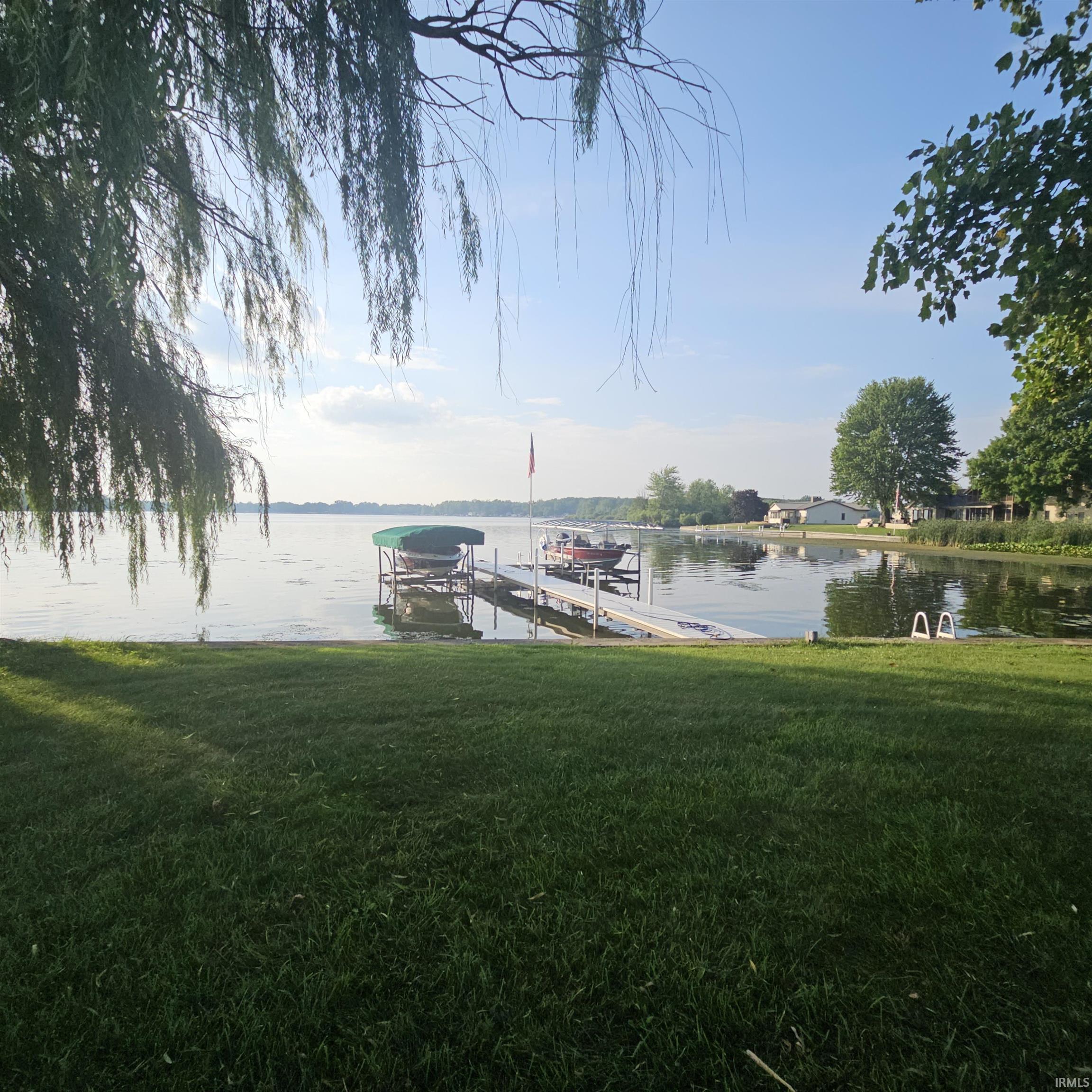 Image 2: Dock with boat lift, a water view, and a lawn, Dock