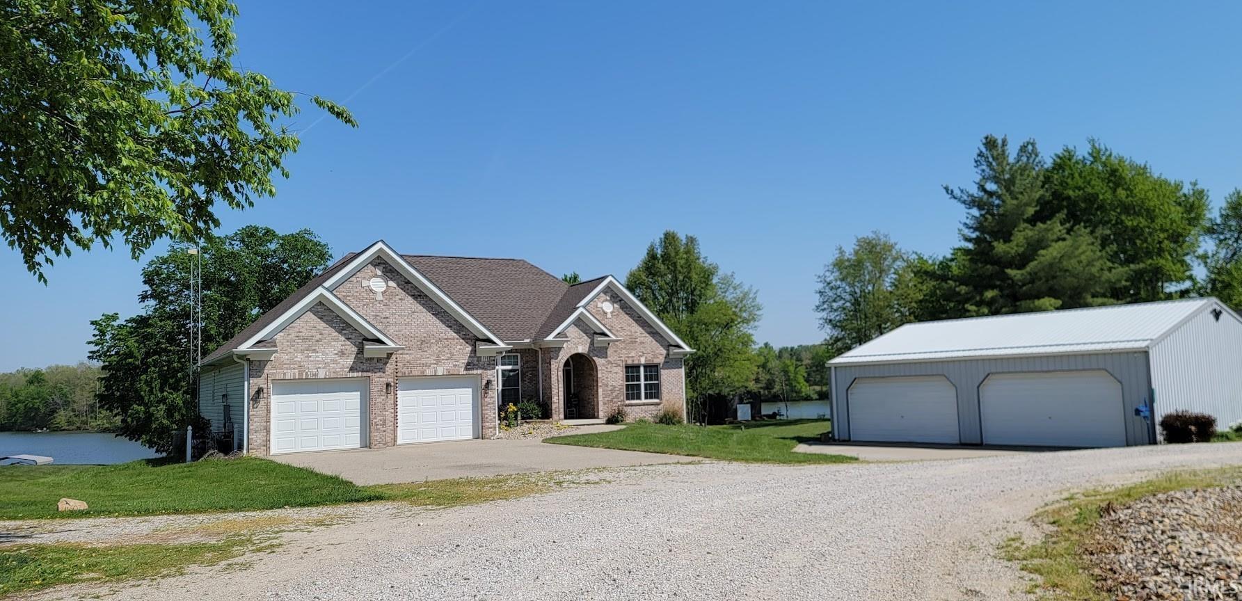 Image 3: Brick exterior residence with an attached two-car garage, separate three-bay garage structure, and waterfront access, Front Of Structure