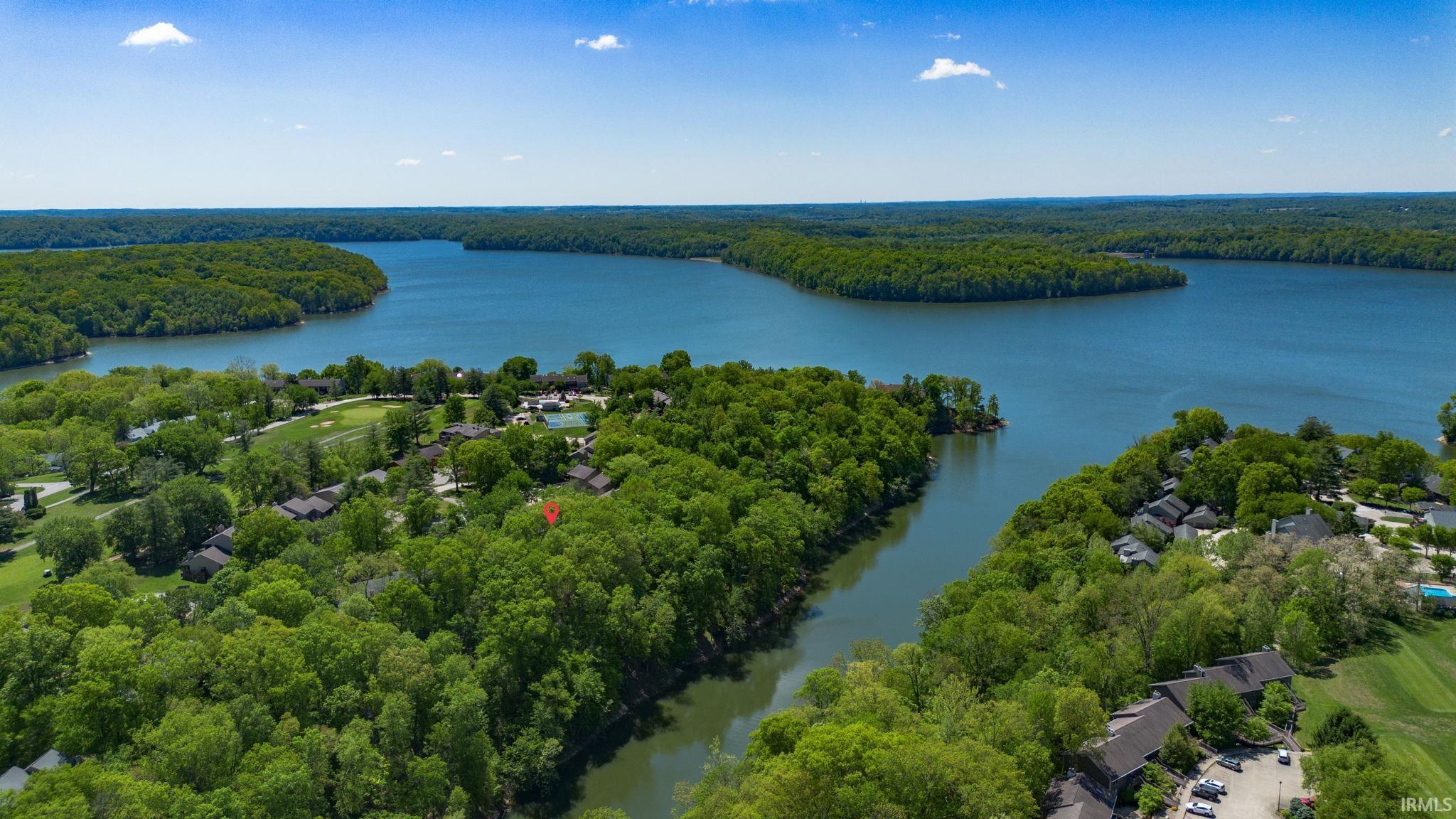 Image 0: Expansive waterfront property bordered by mature trees and a serene body of water, Aerial View