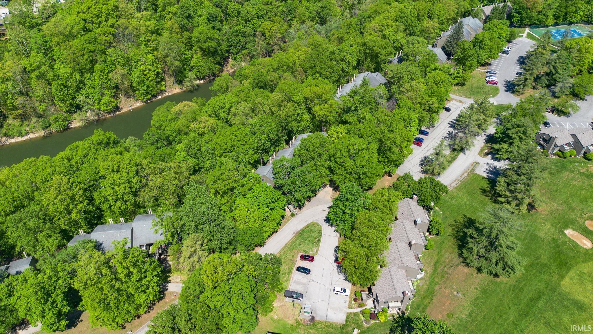 Image 3: Aerial perspective showcasing multiple residential structures with gray shingle roofs, surrounded by dense mature trees, Aerial View
