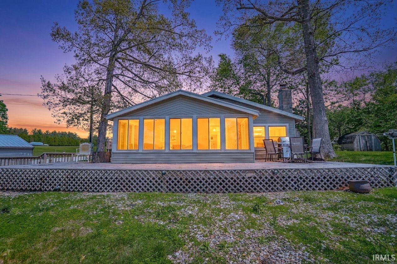 Image 3: Expansive wooden deck with lattice skirting, featuring a spacious sunroom with multiple large windows, View - Front Yard