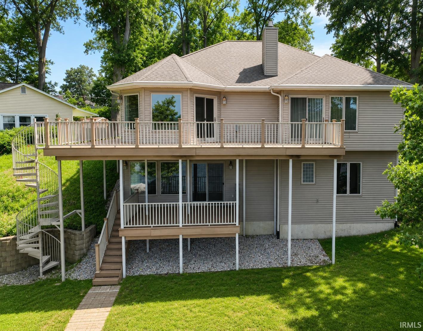 Image 0: Multi-level property featuring a large upper deck with wood railings, a lower covered patio, and a spiral staircase providing exterior access - this is the 'lake side' view., Back Of Structure Image 0: Multi-level property featuring a large upper deck with wood railings, a lower covered patio, and a spiral staircase providing exterior access - this is the 'lake side' view., Back Of Structure