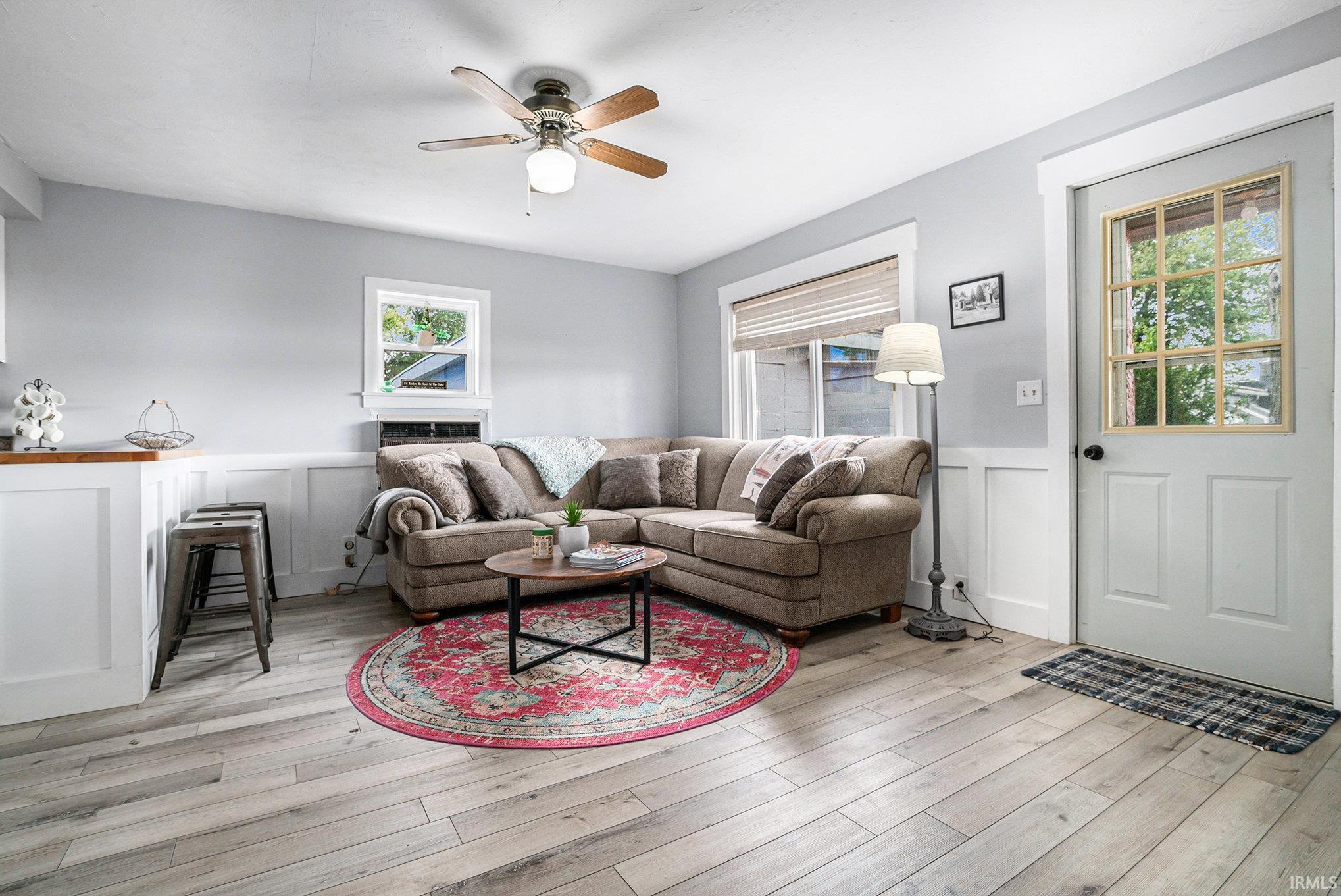 Image 2: Living area featuring a decorative wall, wainscoting, a ceiling fan, and light wood-type flooring, Living Room