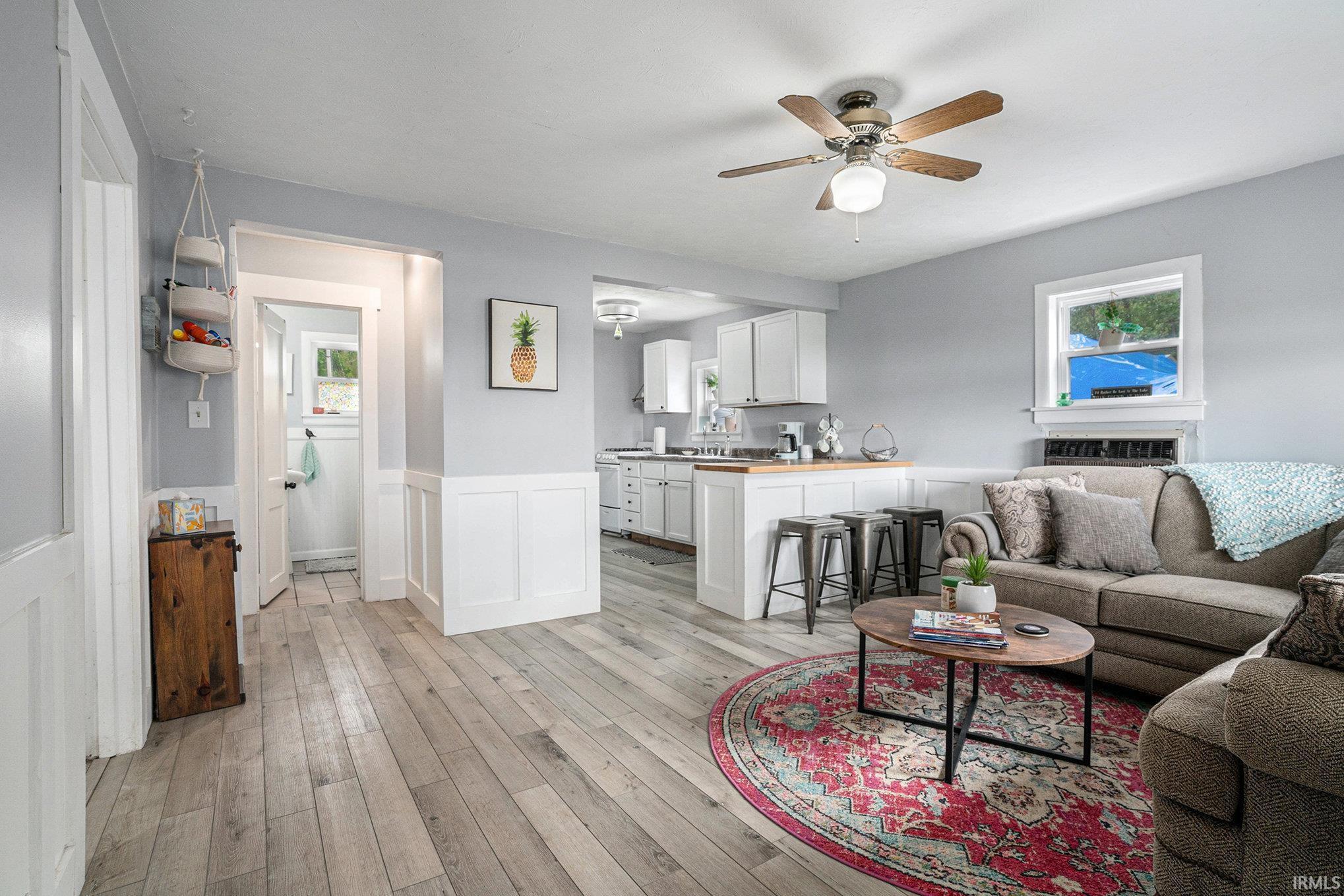 Image 3: Living room featuring a ceiling fan, a wainscoted wall, light wood finished floors, and a decorative wall, Living Room