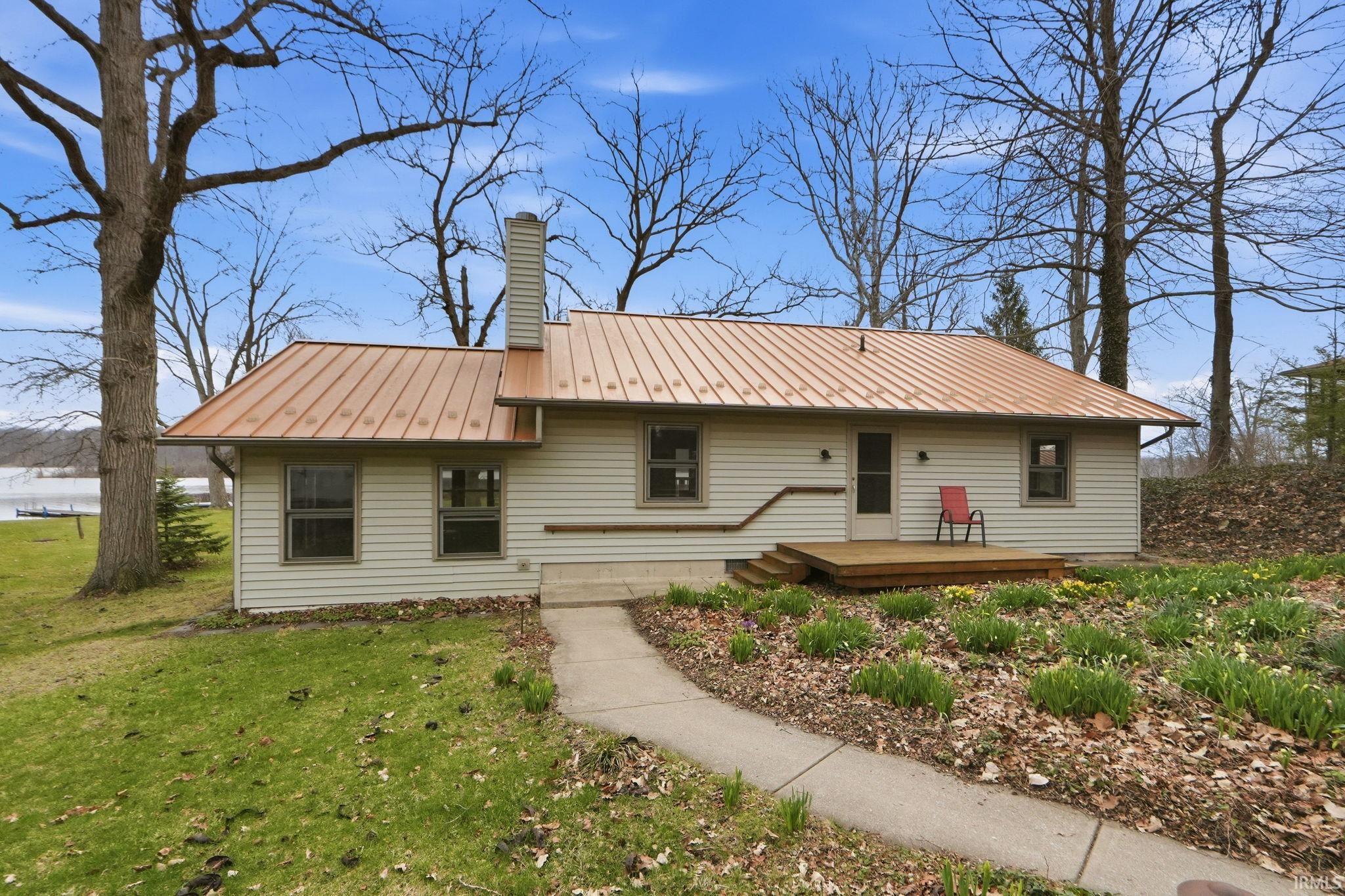 Image 1: View of front of house with a standing seam roof, a chimney, a front yard, and a wooden deck, Front Of Structure