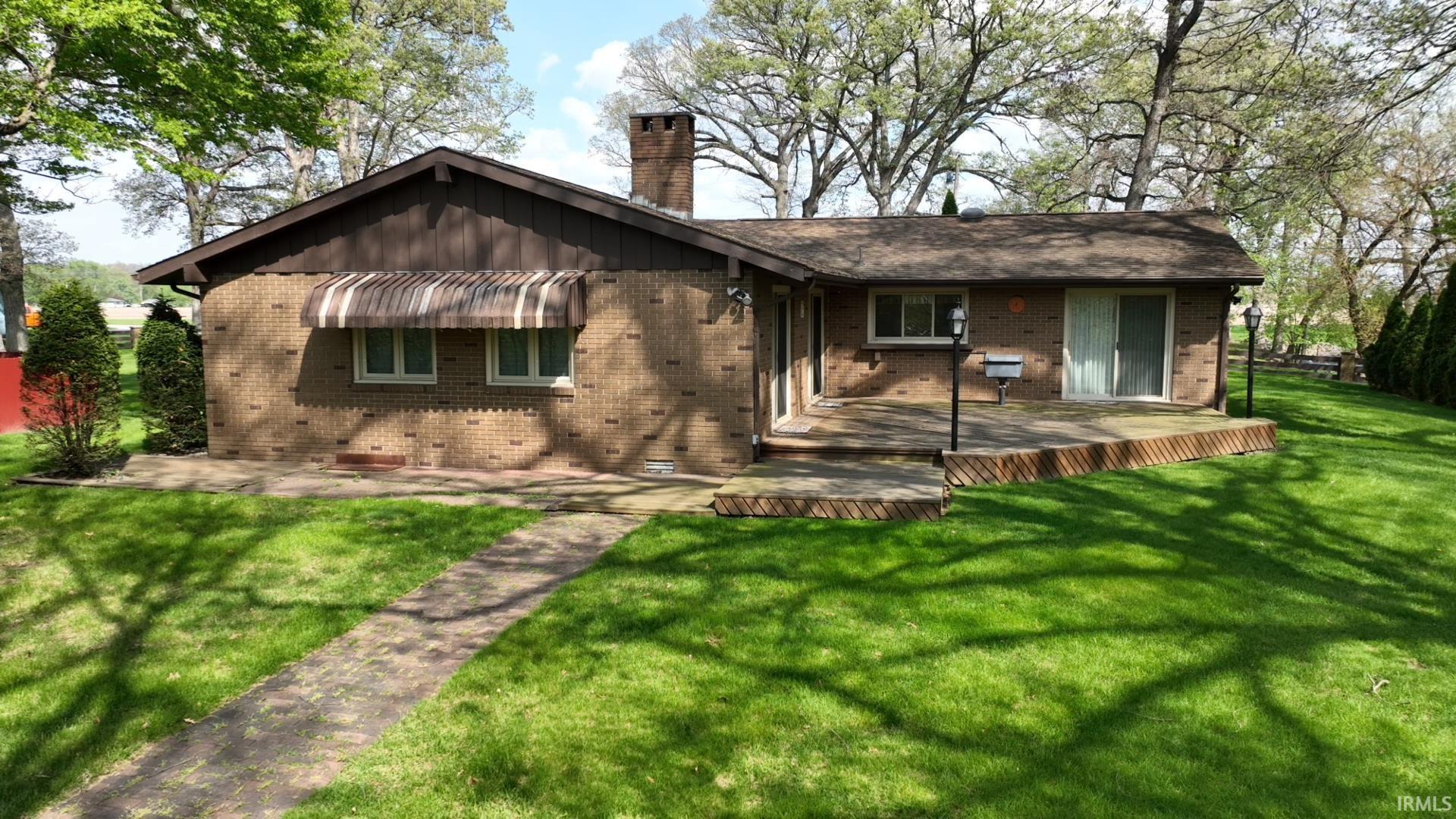 Image 3: Brick exterior residence featuring a wood deck, sliding glass door access, and a stone pathway, Back Of Structure Image 3: Brick exterior residence featuring a wood deck, sliding glass door access, and a stone pathway, Back Of Structure