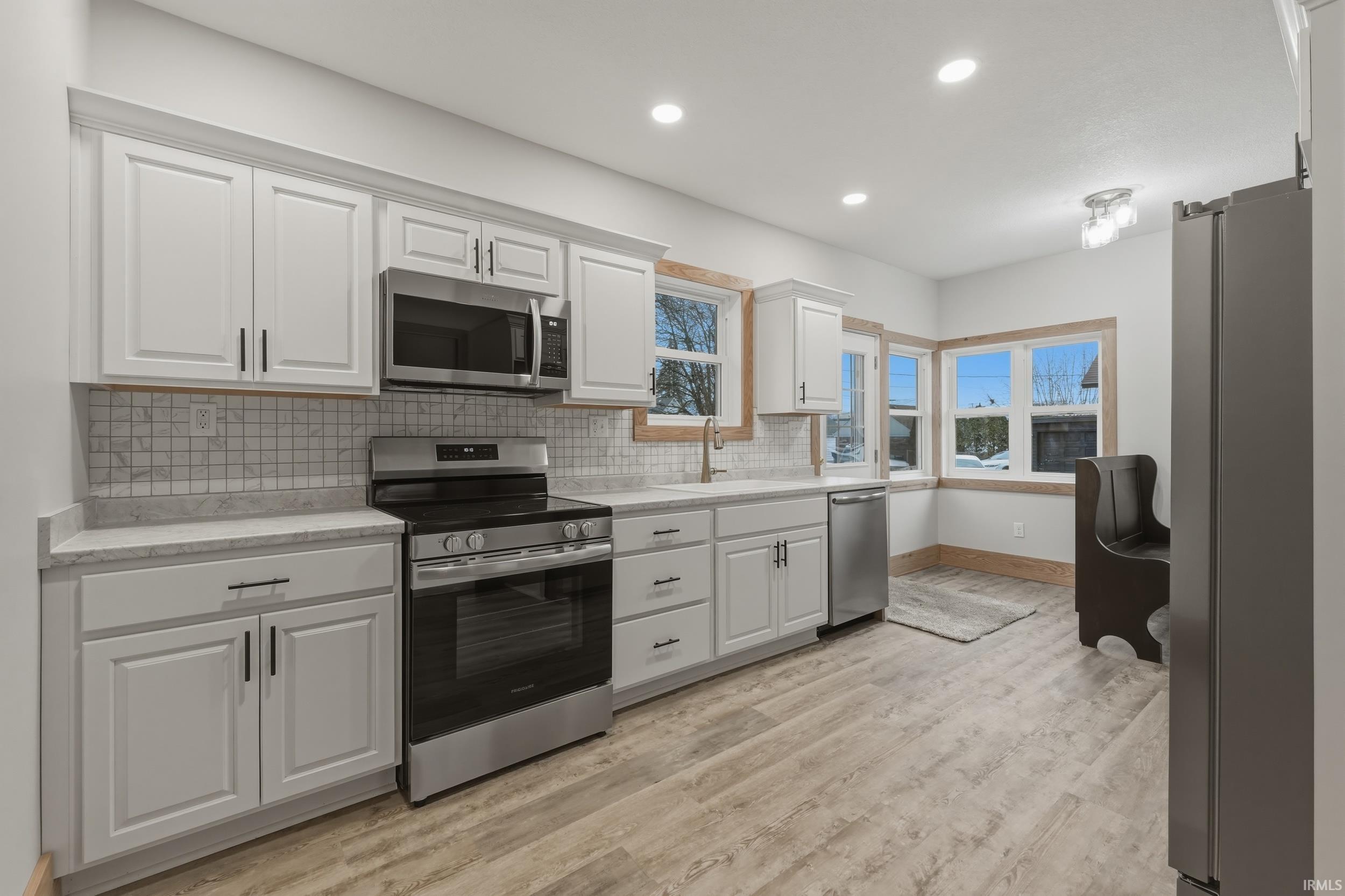Image 1: Kitchen with stainless steel appliances, light countertops, white cabinetry, light wood finished floors, and recessed lighting, Kitchen