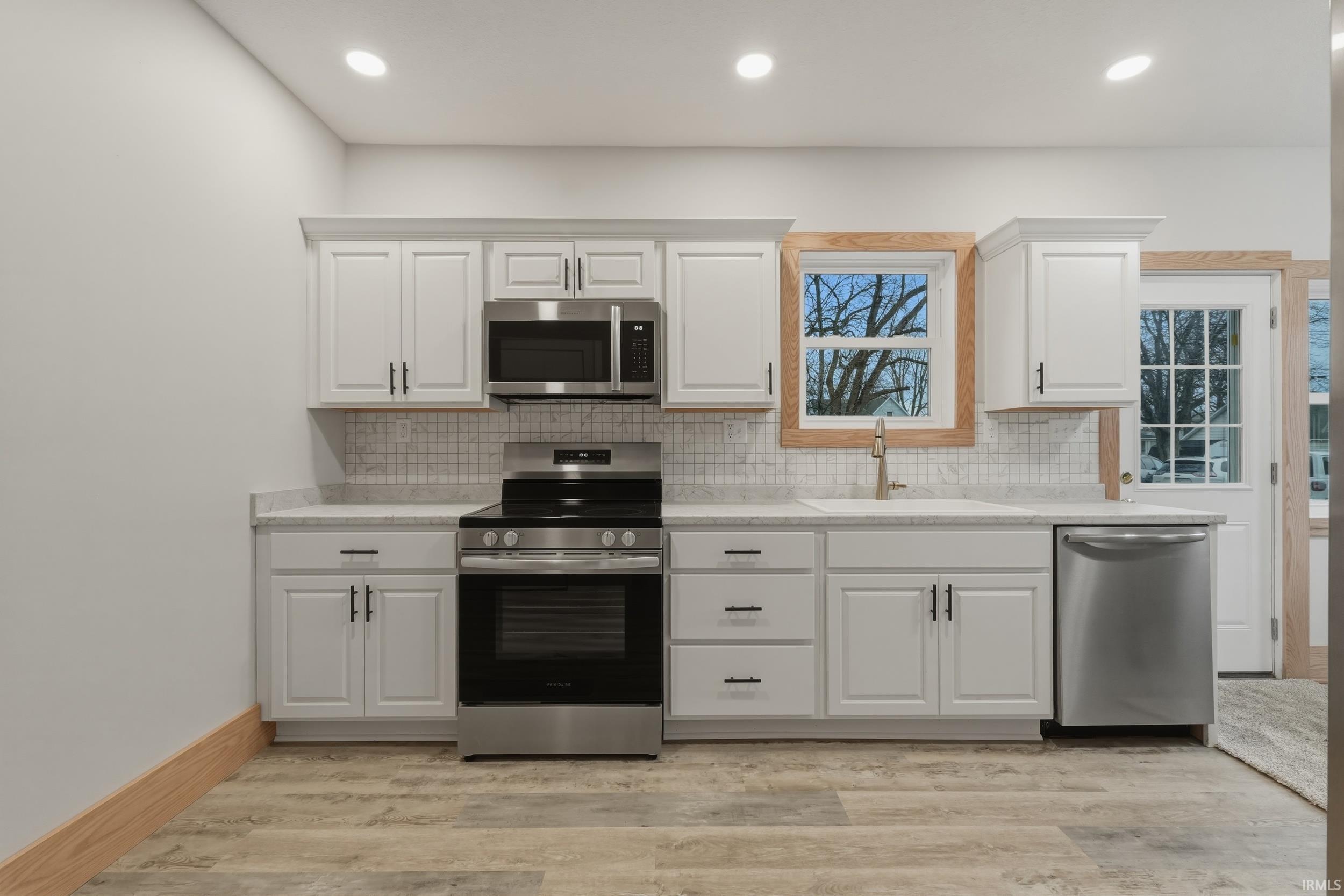 Image 2: Kitchen featuring stainless steel appliances, white cabinets, backsplash, light wood-style floors, and recessed lighting, Kitchen