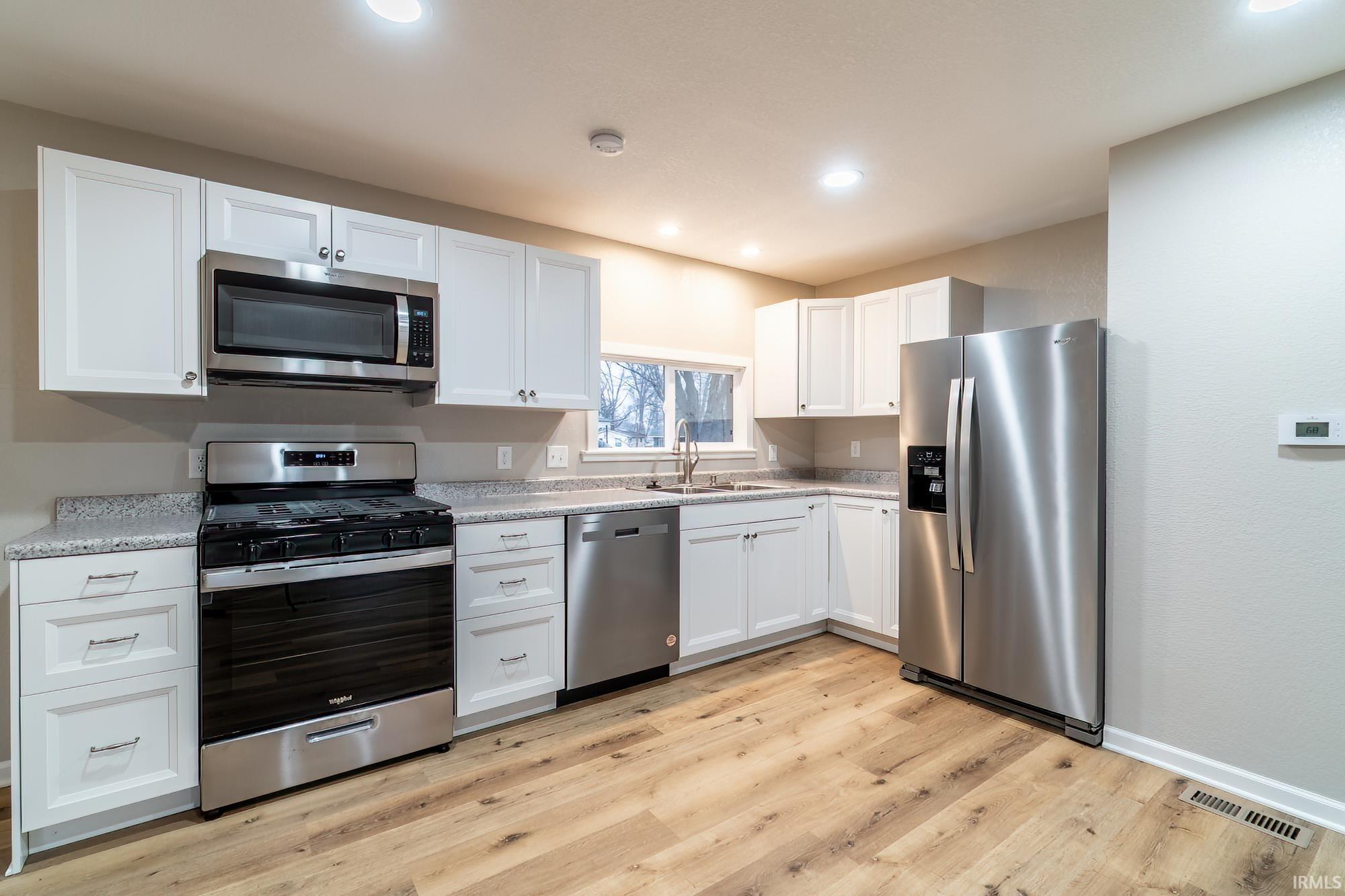 Image 1: Kitchen featuring stainless steel appliances, white cabinets, light wood-style flooring, recessed lighting, and light stone countertops, Kitchen