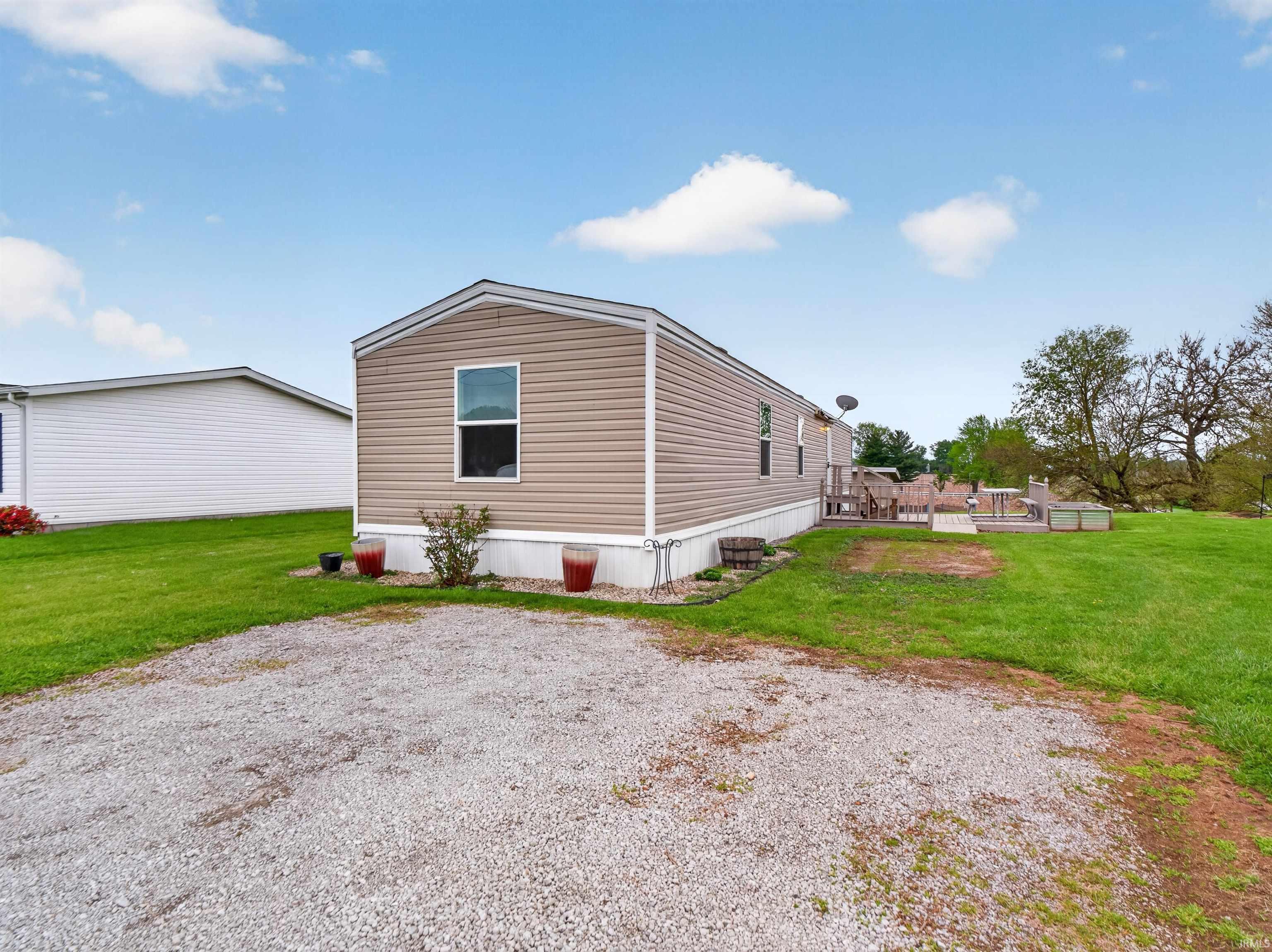 Image 1: Tan horizontal siding exterior with white trim and a gravel driveway, Side Of Structure