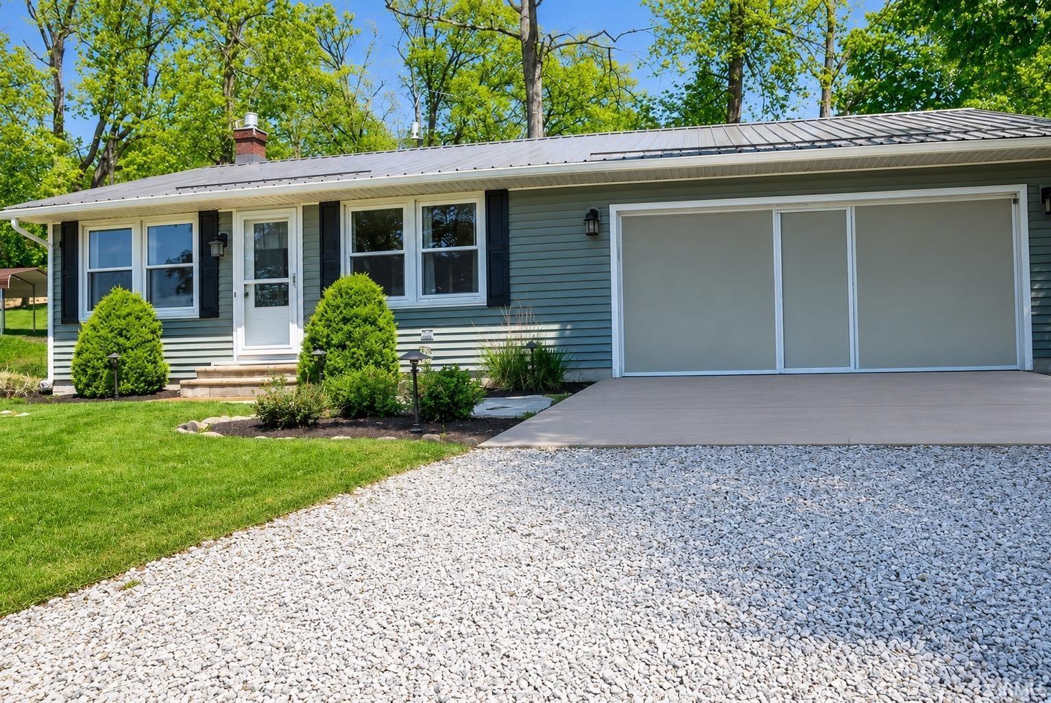 Image 0: Cottage-style residence featuring siding, a gravel driveway, and an attache car garage with sliding screen doors, Front Of Structure Image 0: Cottage-style residence featuring siding, a gravel driveway, and an attache car garage with sliding screen doors, Front Of Structure