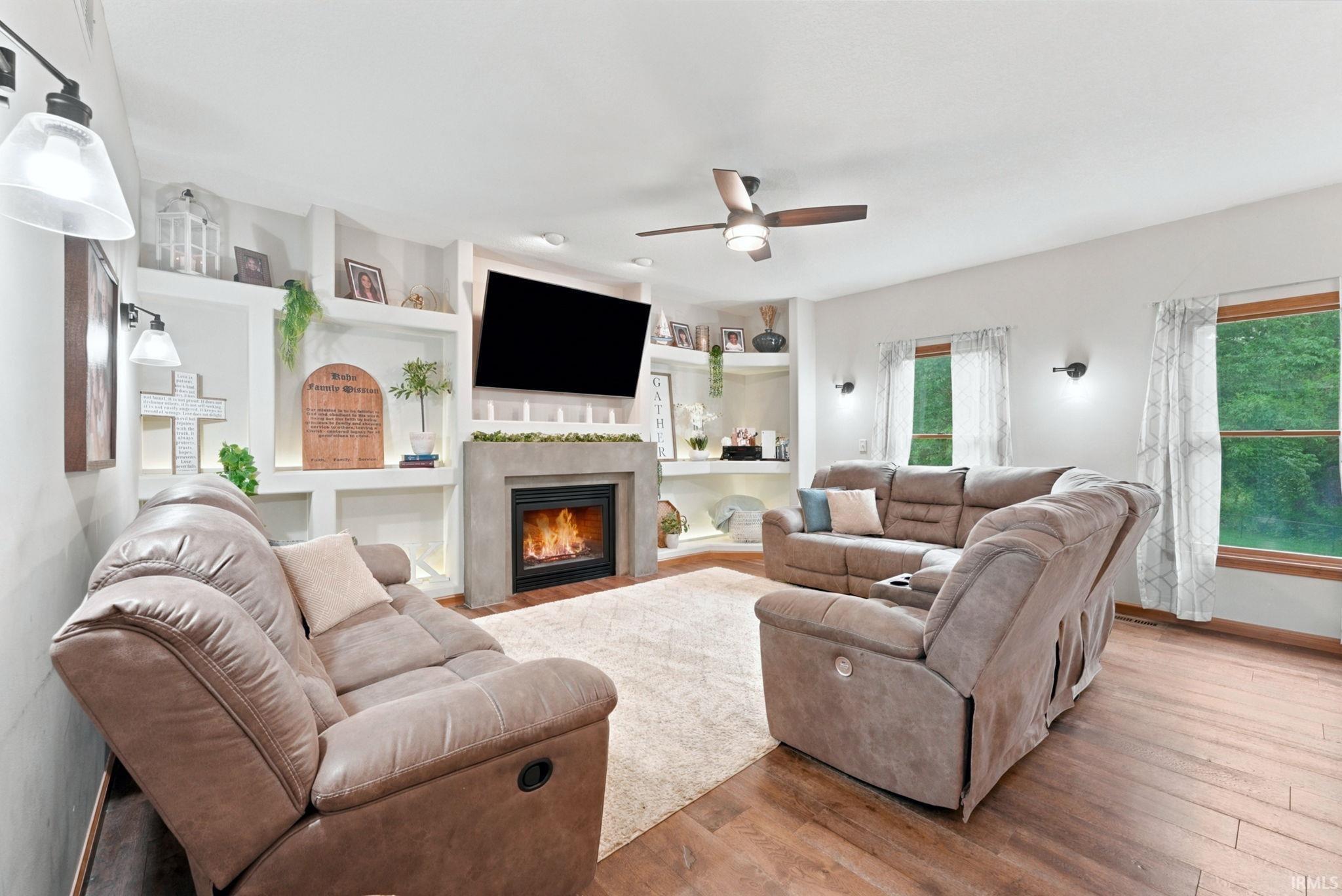 Image 3: Spacious living area featuring wood-finish flooring, a contemporary ceiling fan, and multiple windows, Living Room Image 3: Spacious living area featuring wood-finish flooring, a contemporary ceiling fan, and multiple windows, Living Room
