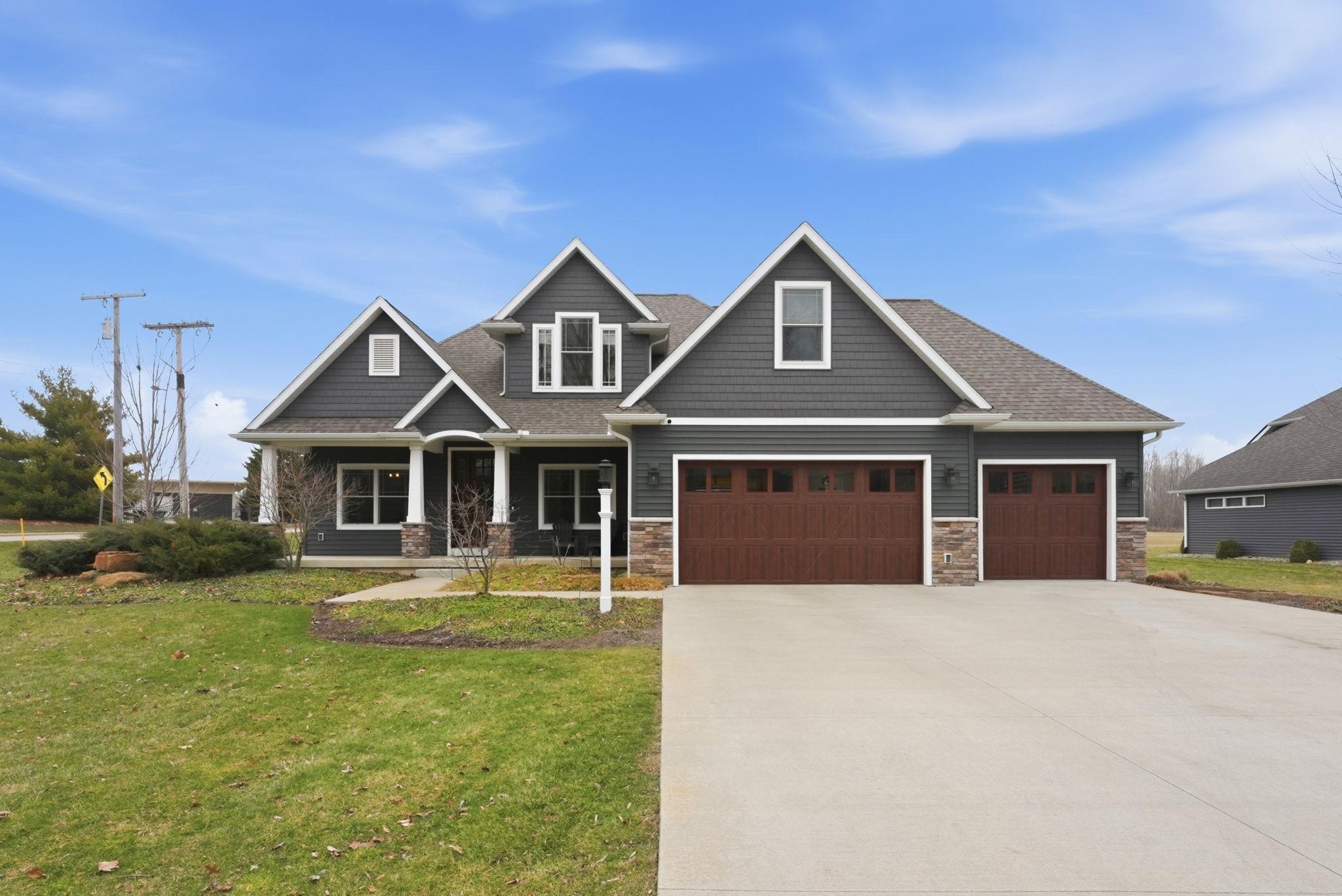 Image 0: Craftsman inspired home featuring a porch, driveway, stone siding, a front yard, and a garage, Front Of Structure