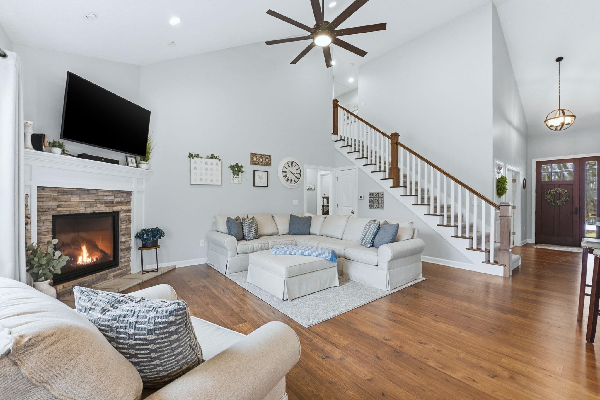 Image 2: Living room with wood-type flooring, vaulted ceiling, a stone fireplace, a ceiling fan, and recessed lighting, Living Room