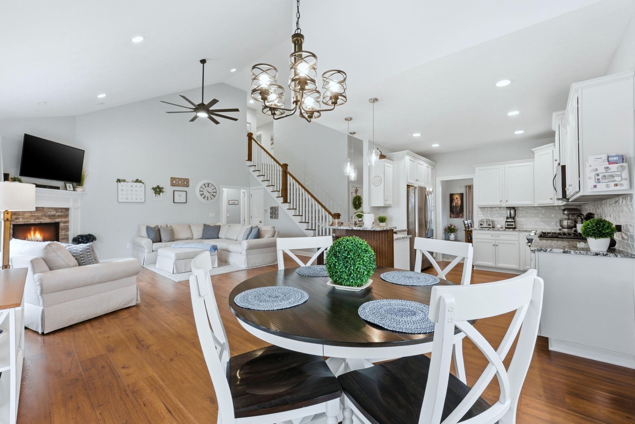 Image 3: Dining space featuring a fireplace, hanging lights, dark wood-style flooring, ceiling fan, and vaulted ceiling, Dining Area
