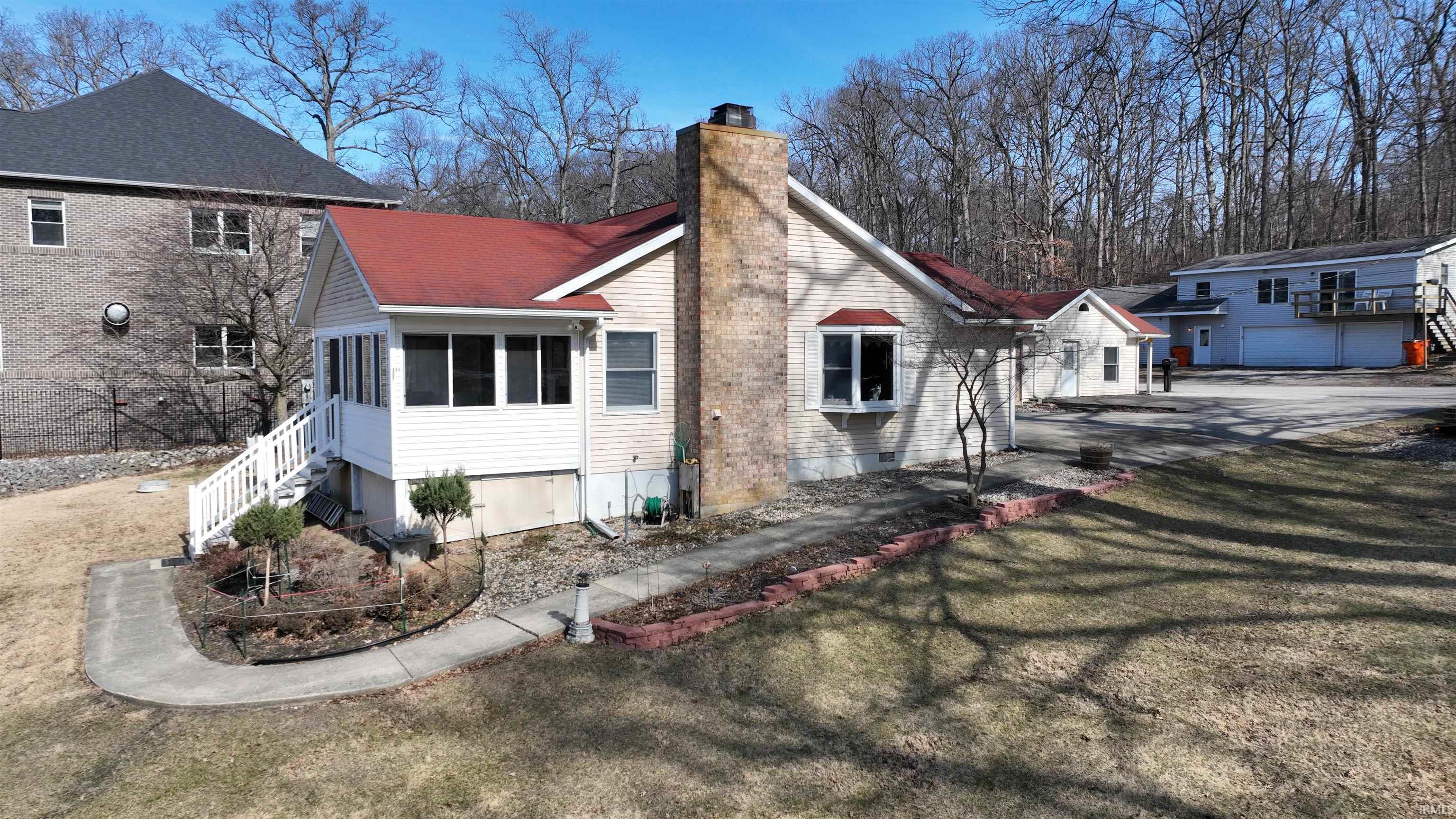 Image 2: Back of property featuring a sunroom, a chimney, and a lawn, Back Of Structure