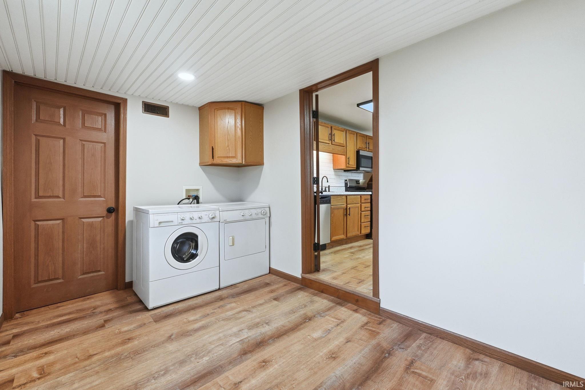 Image 1: Laundry area with light wood-style floors, washer and dryer, cabinet space, and recessed lighting, Laundry