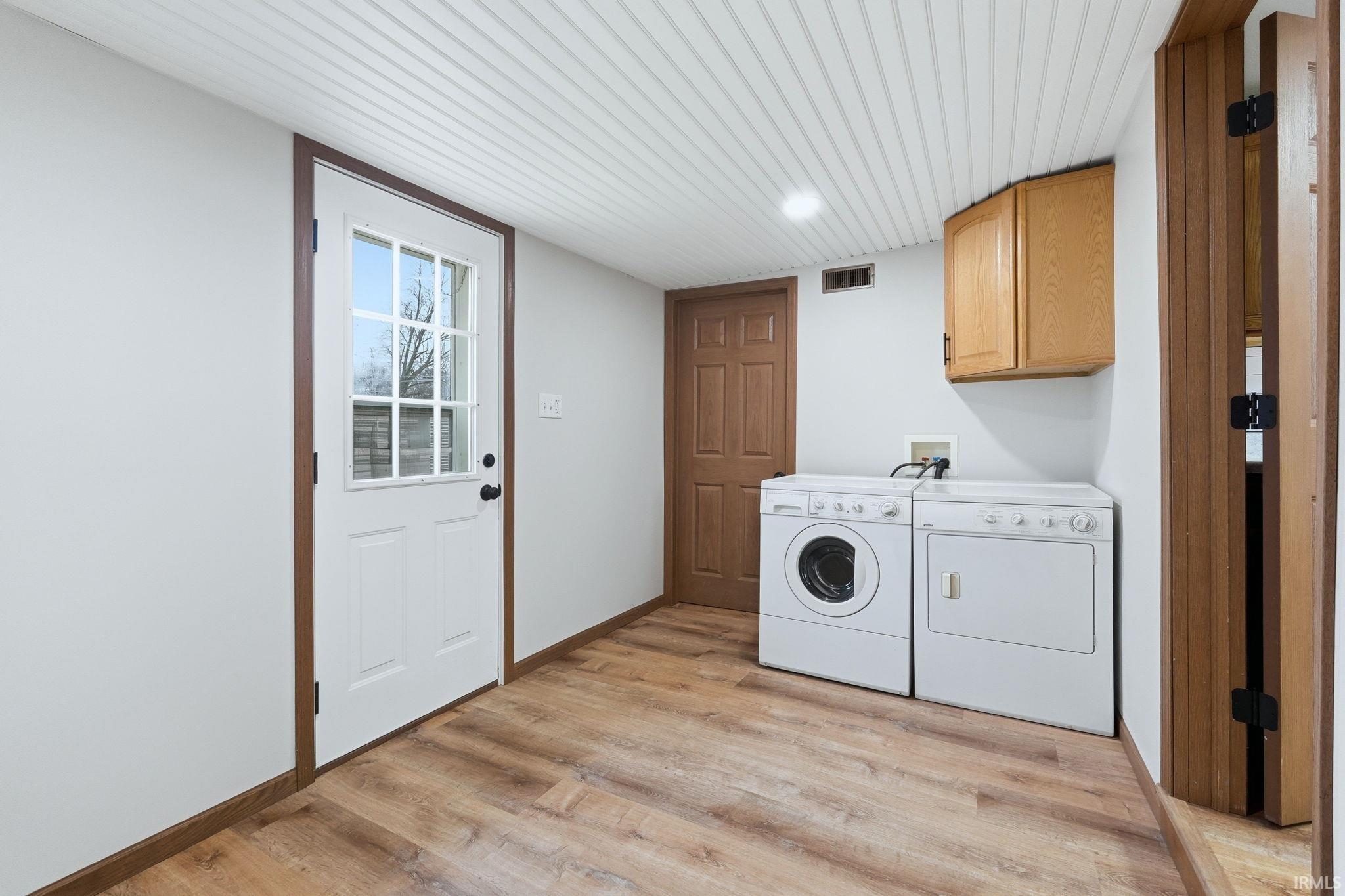 Image 2: Laundry room with light wood-type flooring, independent washer and dryer, and cabinet space, Laundry