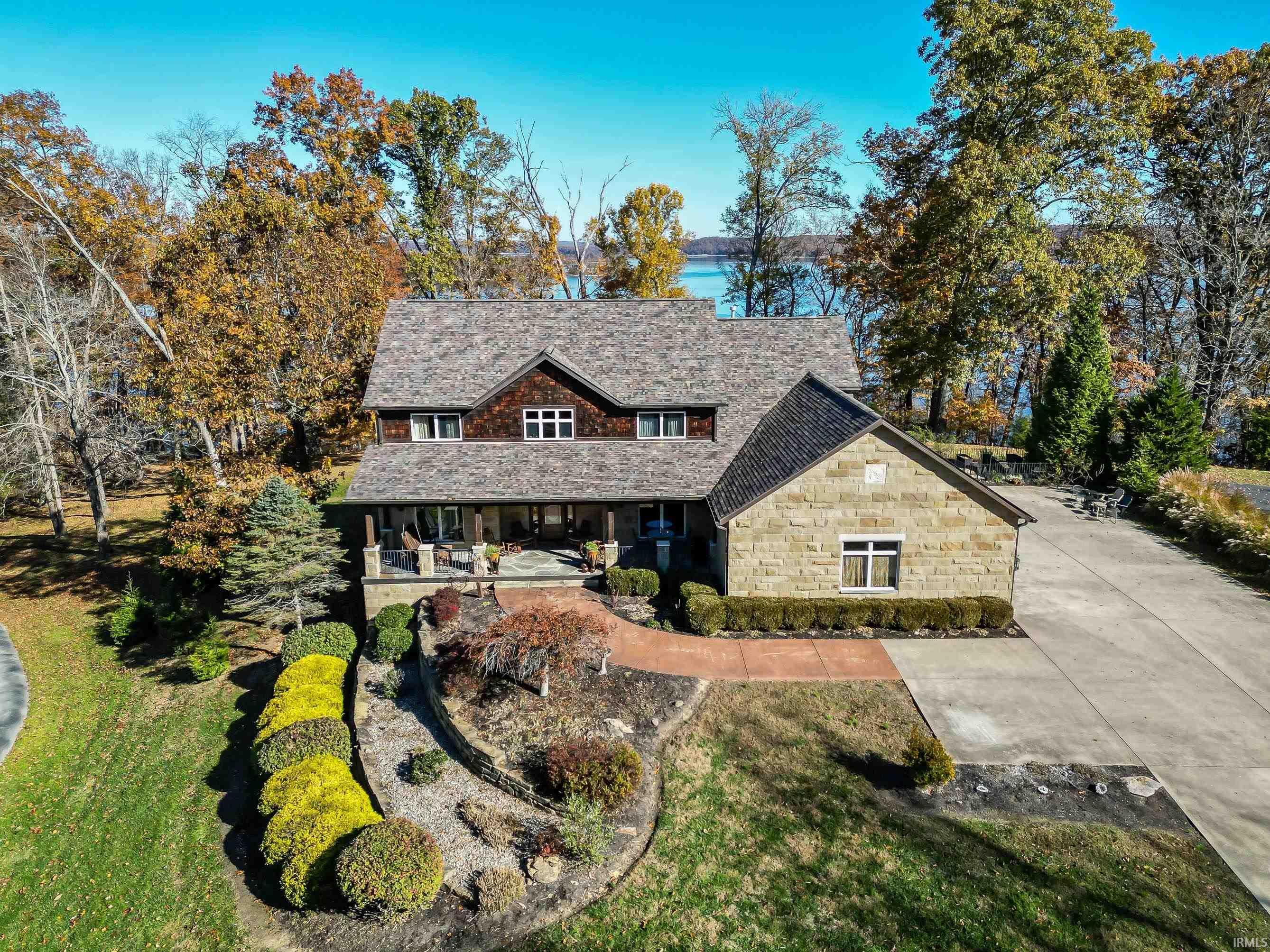 Image 1: Stone and wood-sided residence featuring a shingled roof, covered front porch, and mature landscaping, Front Of Structure Image 1: Stone and wood-sided residence featuring a shingled roof, covered front porch, and mature landscaping, Front Of Structure