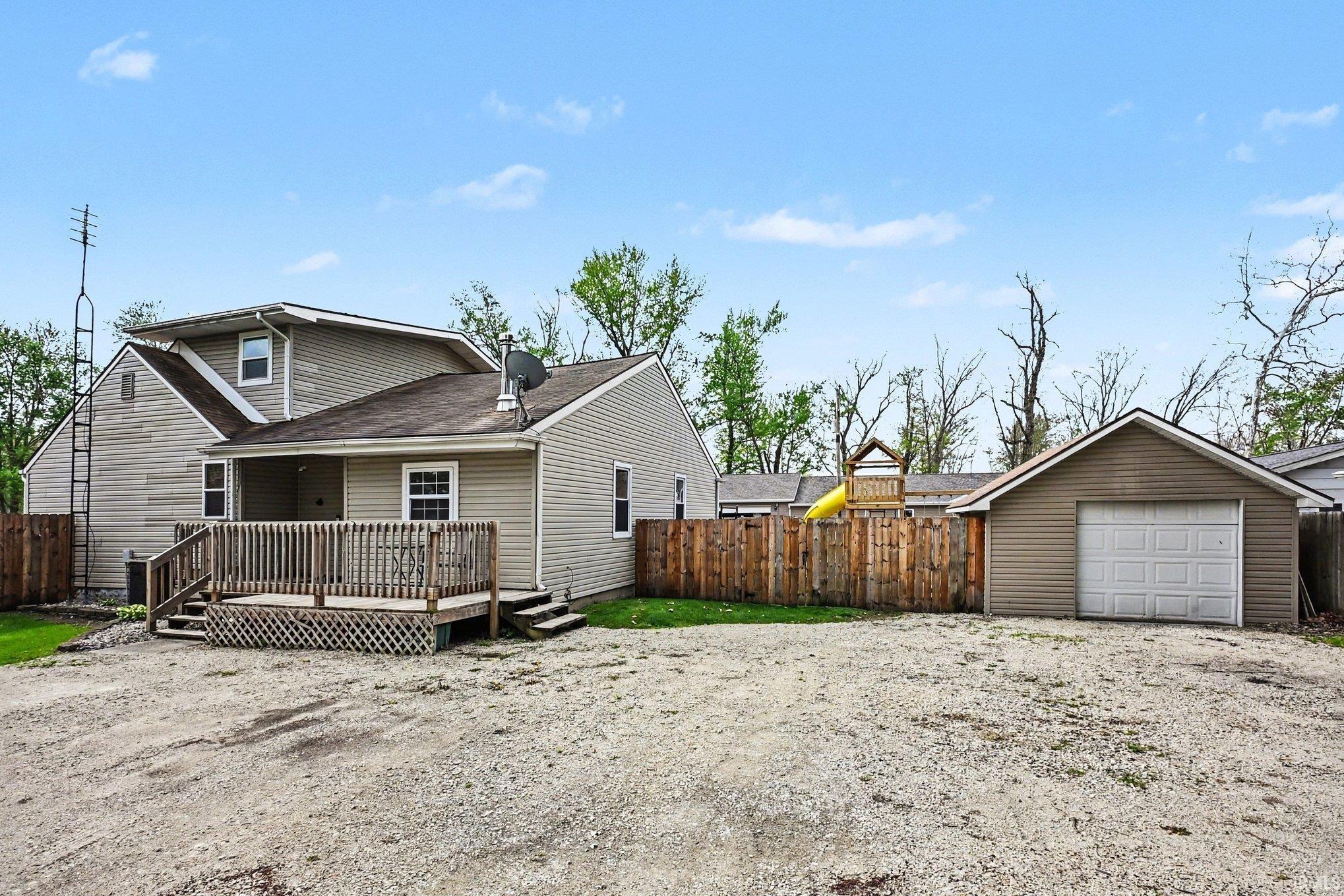 Image 2: Rear exterior featuring a spacious wood deck, tan siding, and a detached single-car garage, View - Second Front Image 2: Rear exterior featuring a spacious wood deck, tan siding, and a detached single-car garage, View - Second Front
