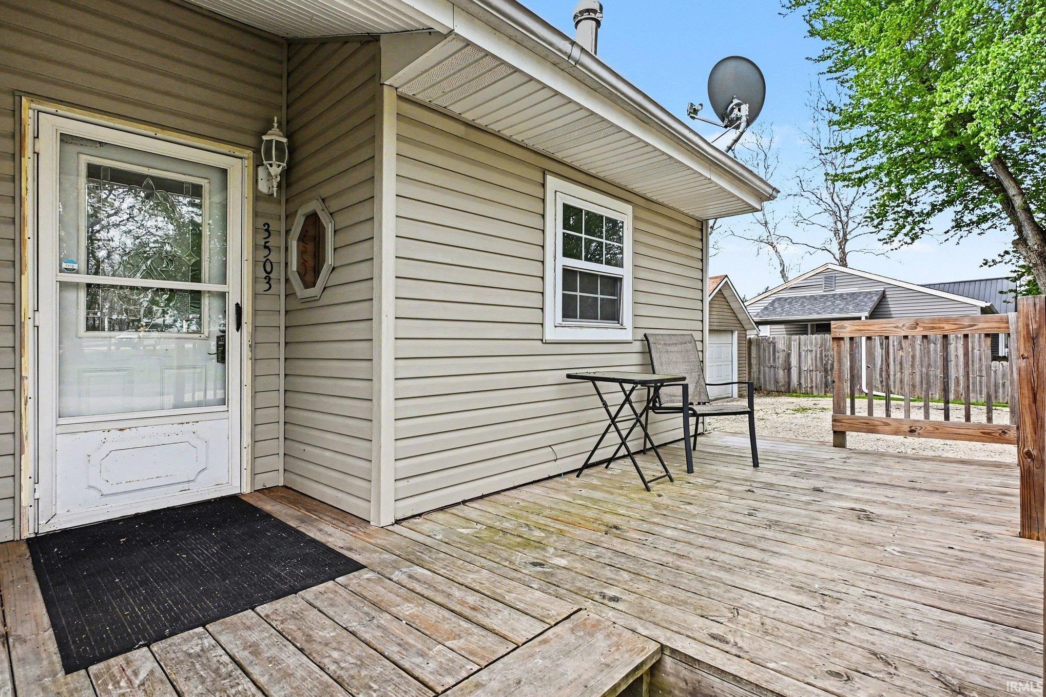 Image 3: Front entrance with a storm door, an exterior wall light fixture, and horizontal siding, Deck Image 3: Front entrance with a storm door, an exterior wall light fixture, and horizontal siding, Deck