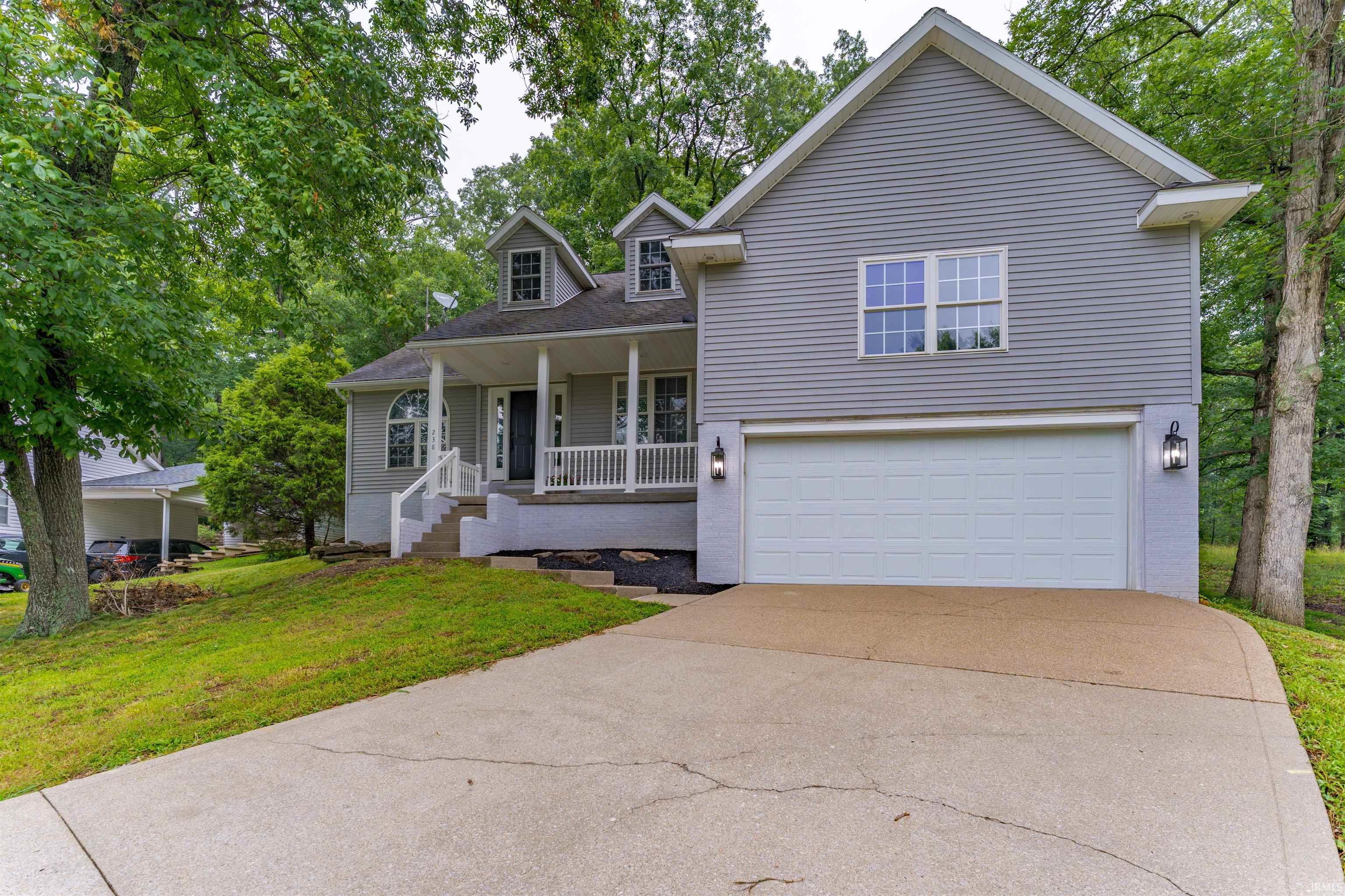 Image 0: Tri-level home featuring a front yard, covered porch, an attached garage, driveway, and brick siding, Front Of Structure