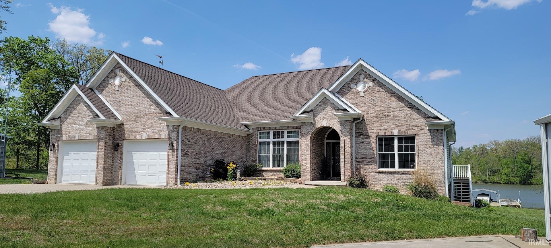 Image 0: Brick exterior residence featuring a multi-gabled roofline, an arched entry, a two-car garage, and waterfront access with a dock, Front Of Structure