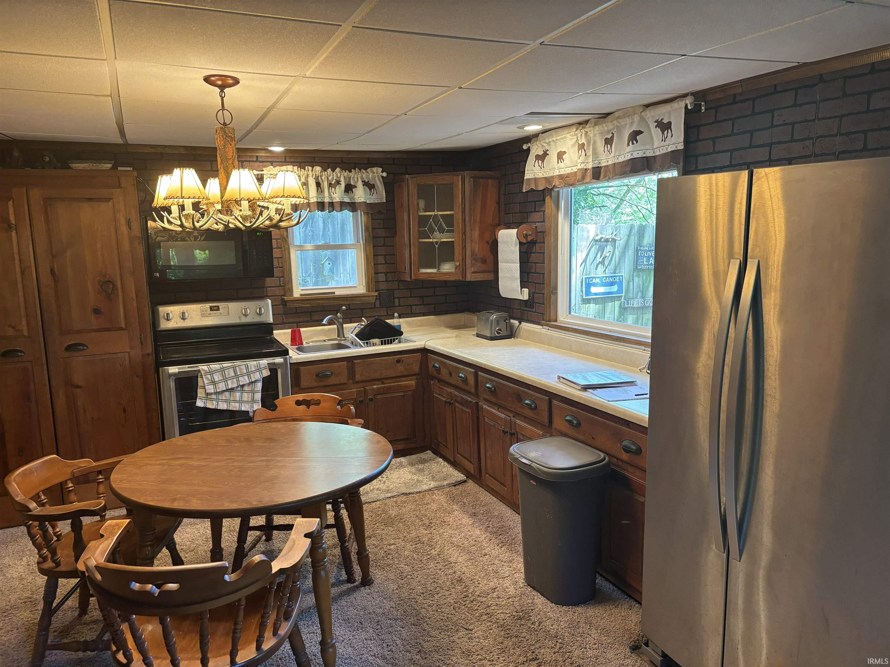 Image 2: Kitchen featuring a stainless steel refrigerator, dark wood cabinetry, a built-in oven with an overhead microwave, and a drop ceiling, Kitchen
