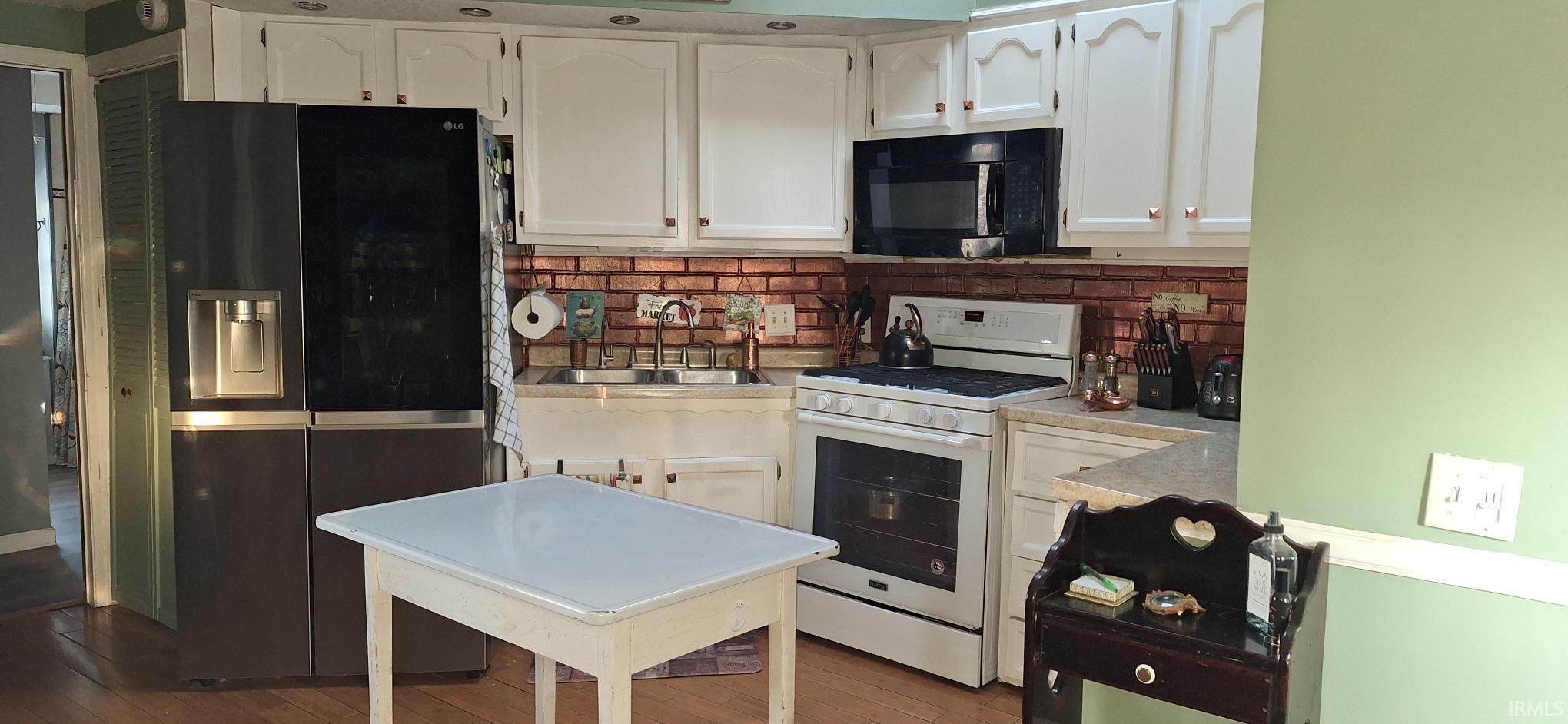 Image 2: Kitchen featuring stainless steel fridge with ice dispenser, white range oven, white cabinets, and light countertops, Kitchen