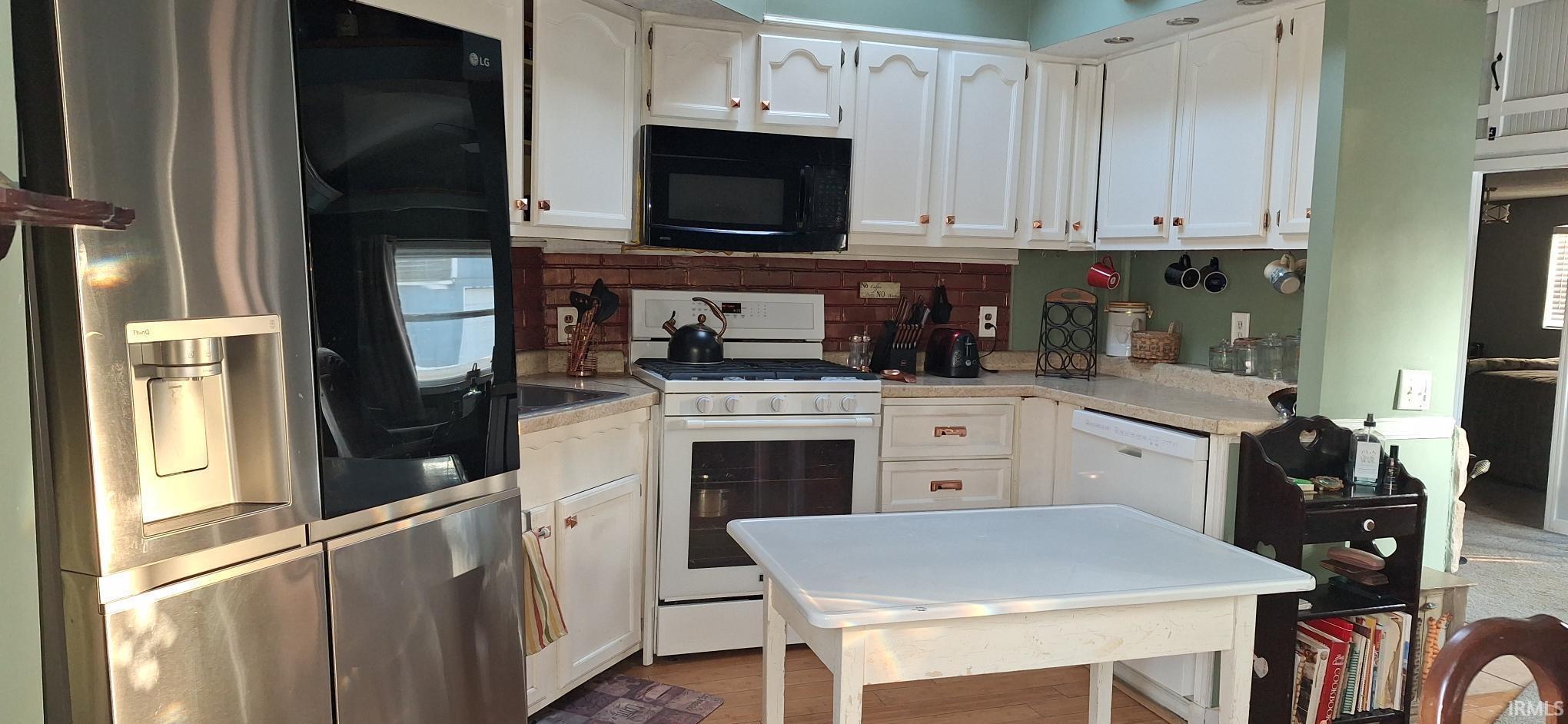 Image 3: Kitchen featuring white appliances, white cabinetry, light countertops, backsplash, and light wood-style flooring, Kitchen