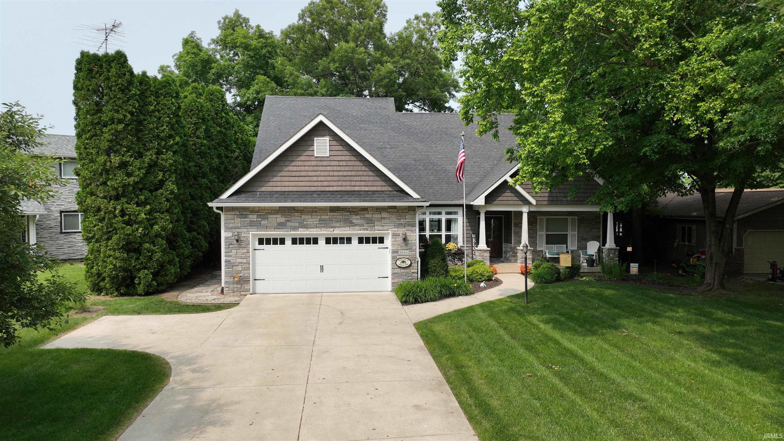 Image 0: Craftsman inspired home with stone siding, a front lawn, covered porch, and concrete driveway, Front Of Structure