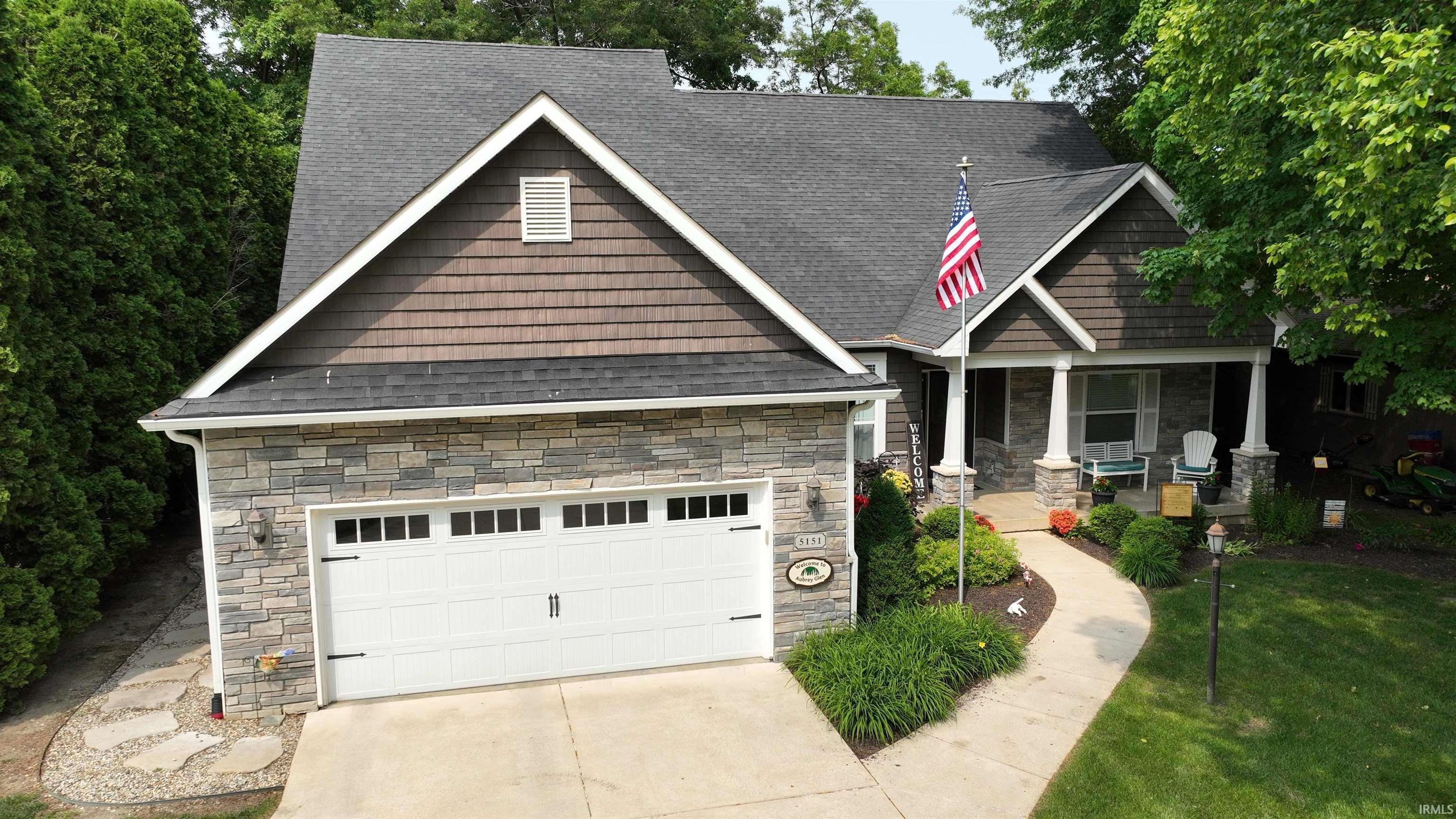 Image 1: Craftsman-style home with stone siding, concrete driveway, a porch, a front lawn, and a shingled roof, Front Of Structure