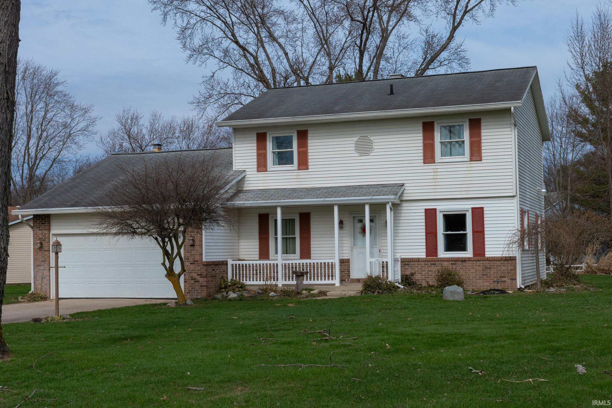 Image 0: Traditional-style home featuring brick siding, covered porch, a garage, and a front lawn, Front Of Structure